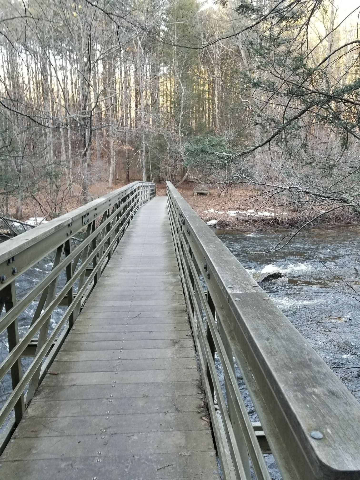 A long wooden bridge crosses a rocky river in a winter forest. - Hidden Valley Preserve loop from Hidden Valley Preserve