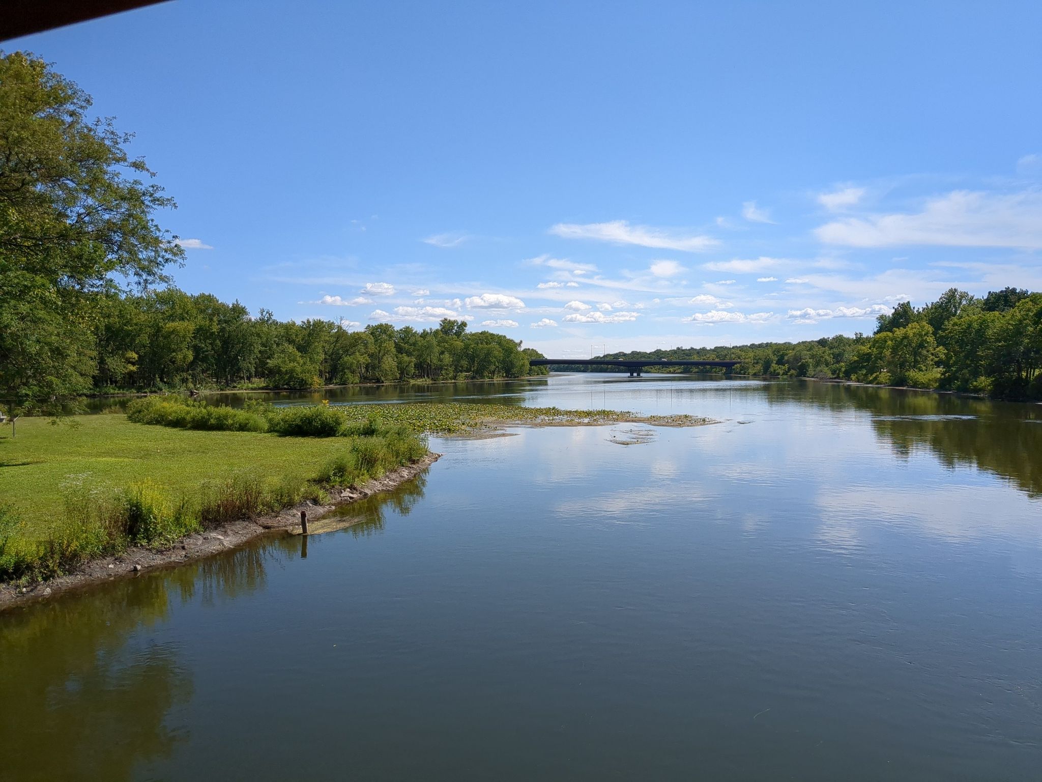 Wide river with distant bridge, green banks, and blue sky with clouds. - Fabyan Japanese Tea Garden – Batavia Depot Museum loop from Geneva Township