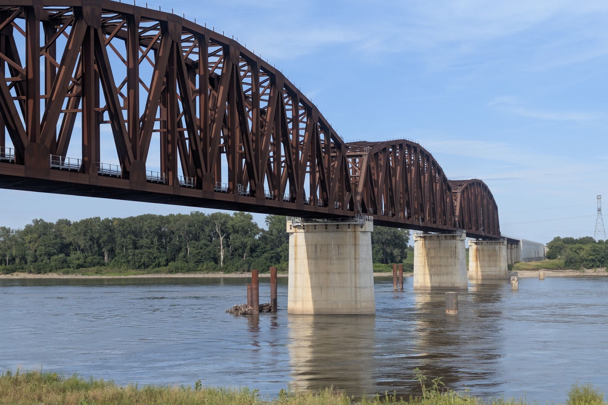 A massive brown truss bridge spans a wide river on a sunny day. - The Grand Basin, Forest Park – Grand Drive loop from Saint Mary's High School