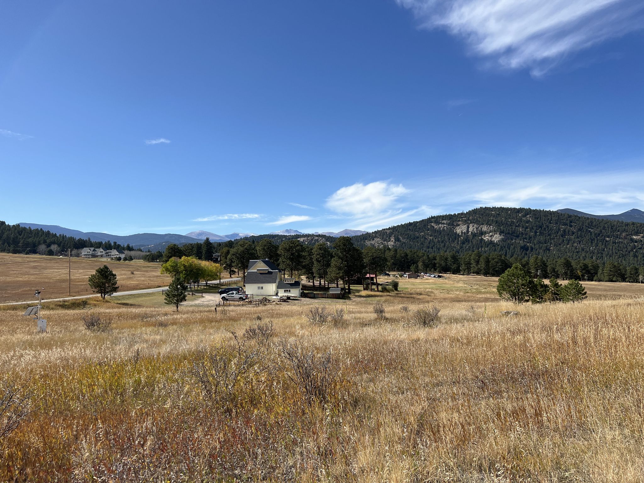 A house in a golden field with distant mountains under a bright blue sky. - Alderfer/Three Sisters Park Loop
