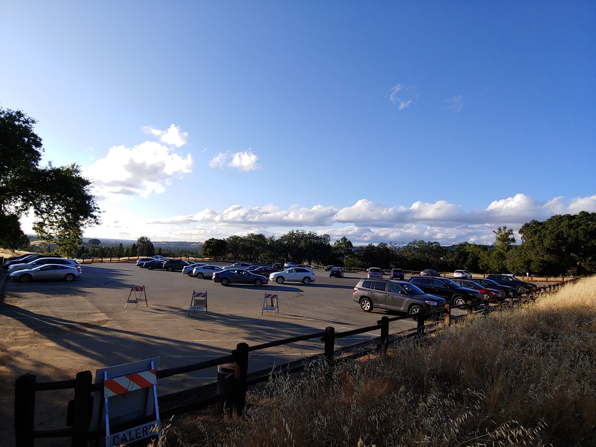 Outdoor parking lot filled with cars under a bright, partly cloudy sky. - Hacienda Trail to Buena Vista Trail