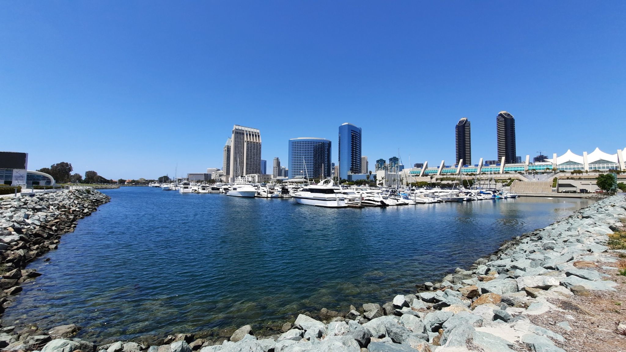 Wide water channel with rocky shores leading to a distant city skyline. - Gaslamp Quarter – The Rady Shell at Jacob Park loop from H Street