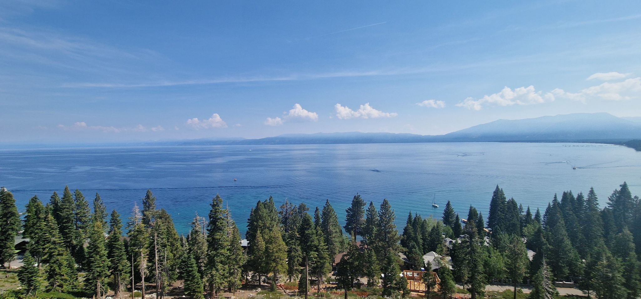 Expansive blue lake bordered by dense green forest under a clear sky. - Lake Tahoe loop
