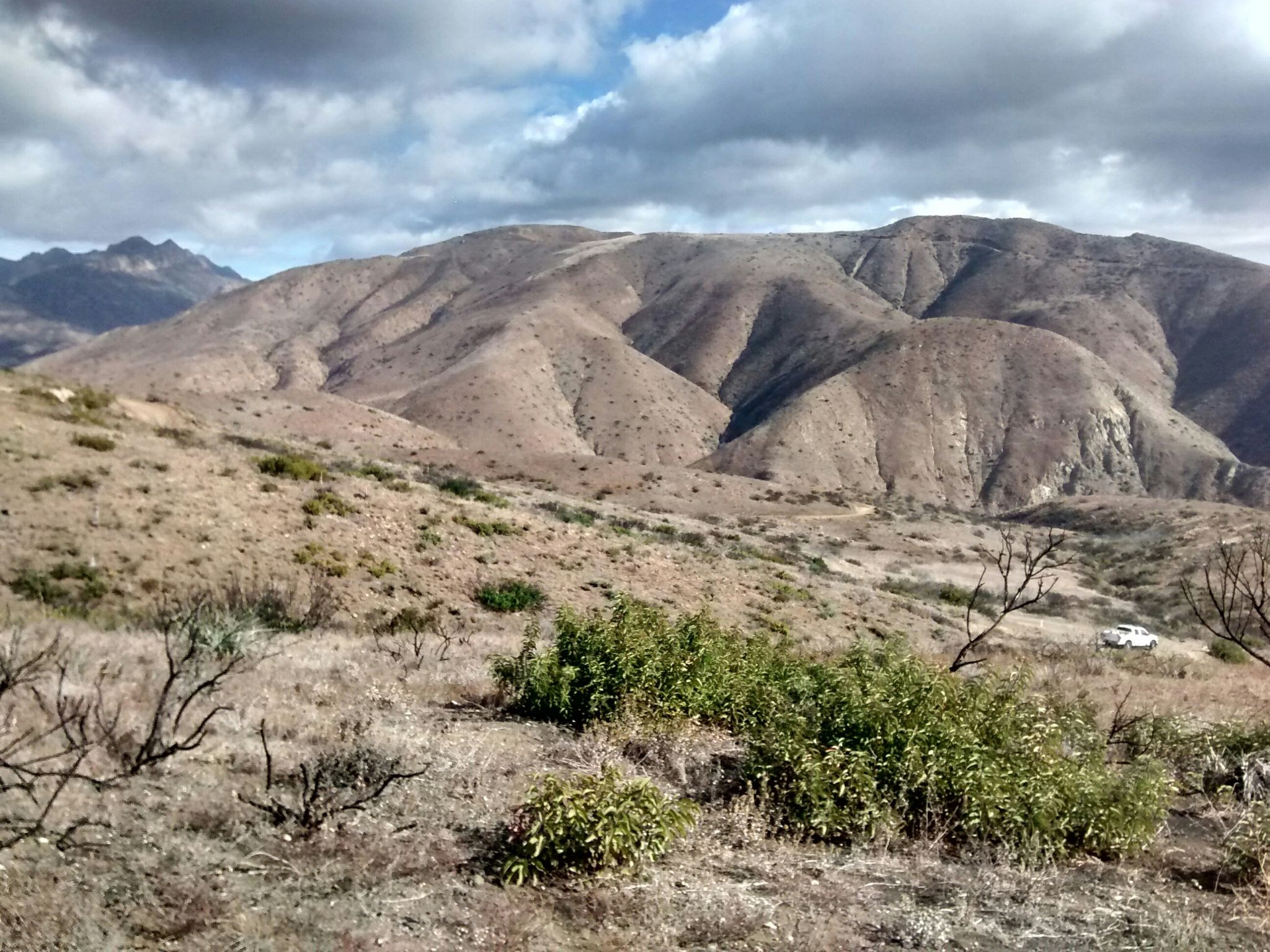 Arid mountains under a cloudy sky, with dry brush in the foreground. - Ray Miller and Overlook Fire Road Loop