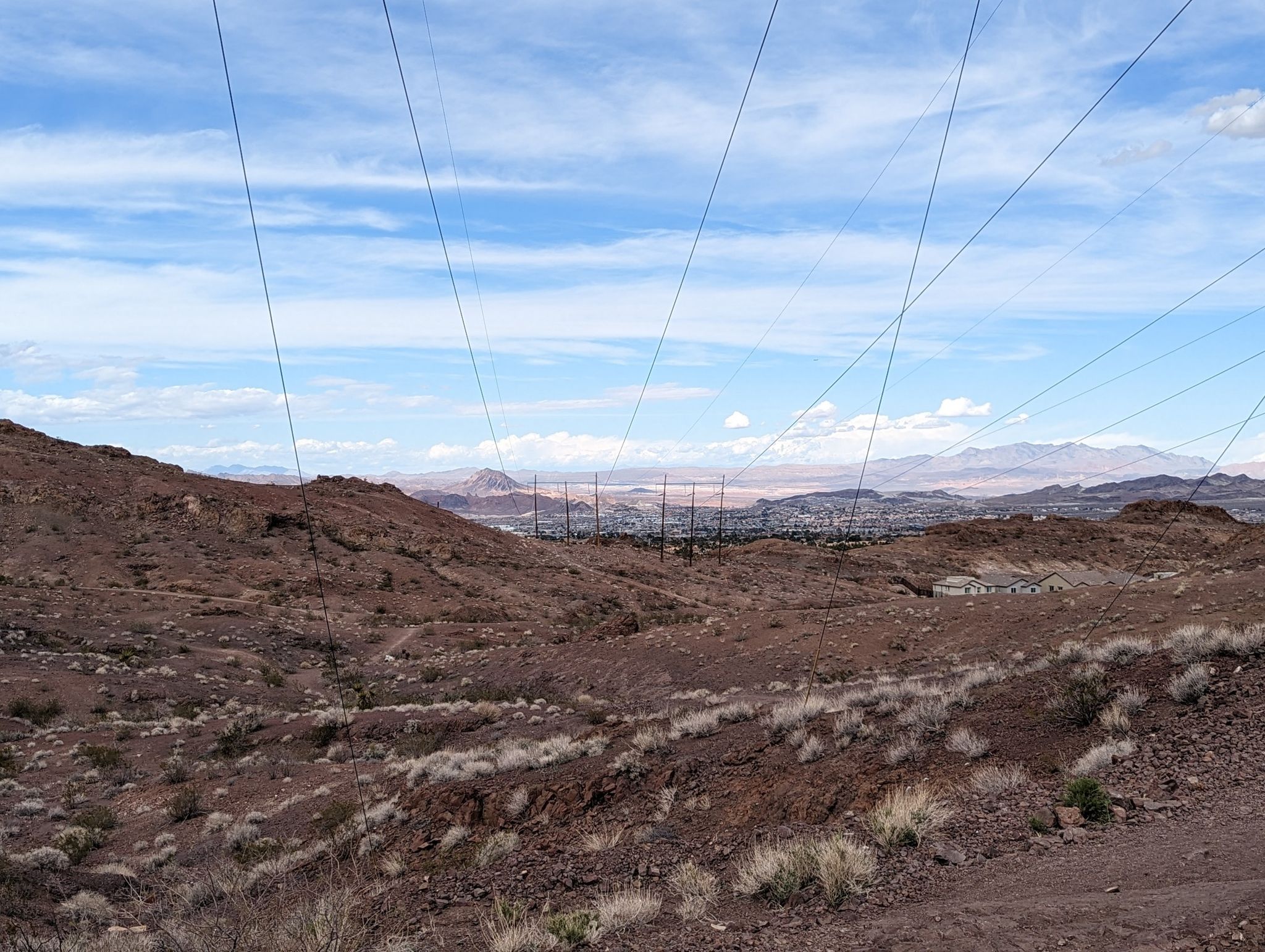 Desert landscape with power lines, brown hills, and distant mountains under a cloudy sky. - McCullough and 601 Loop
