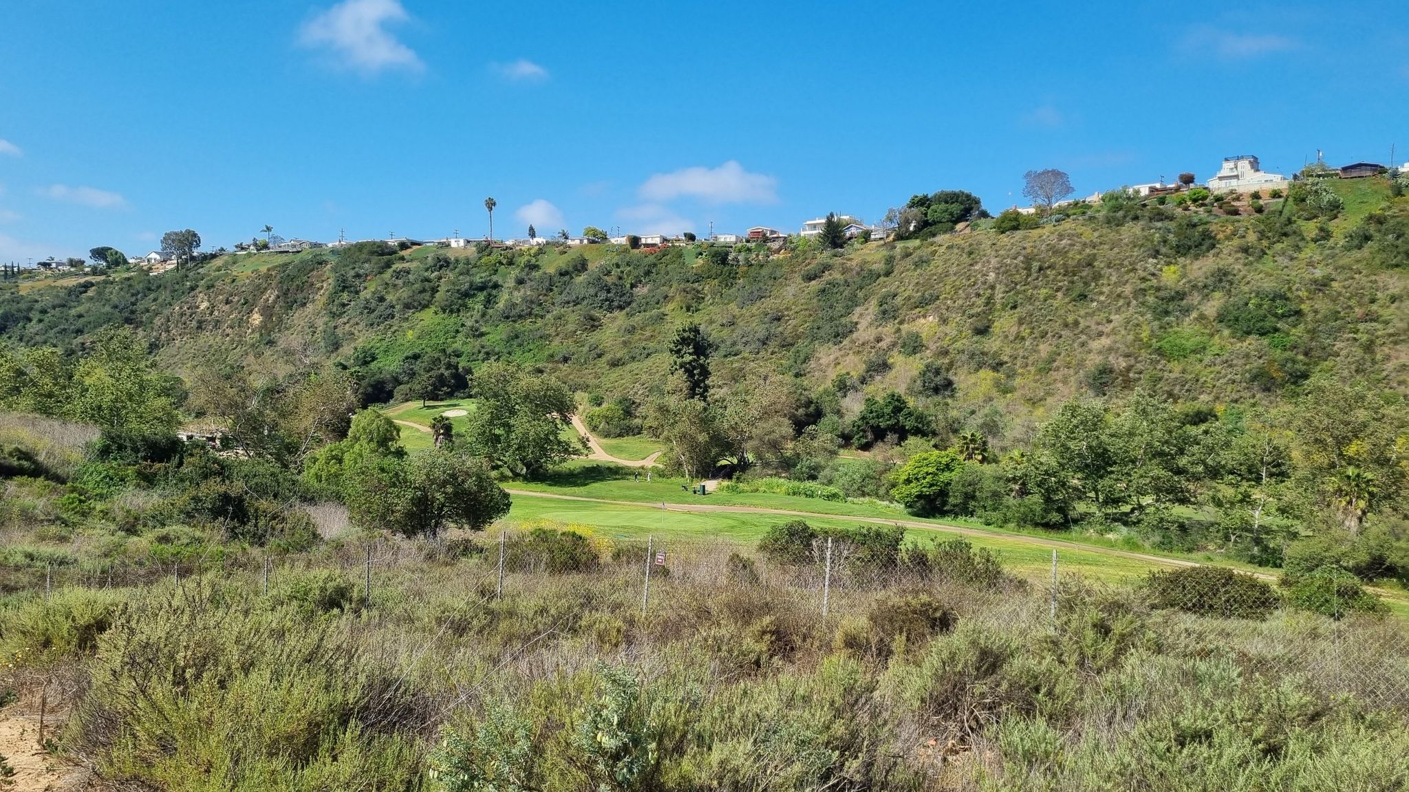 Lush green golf course in a valley surrounded by brushy hills. - Coastal Rail Trail – Leisure Lagoon loop from Balboa Avenue Transit Center