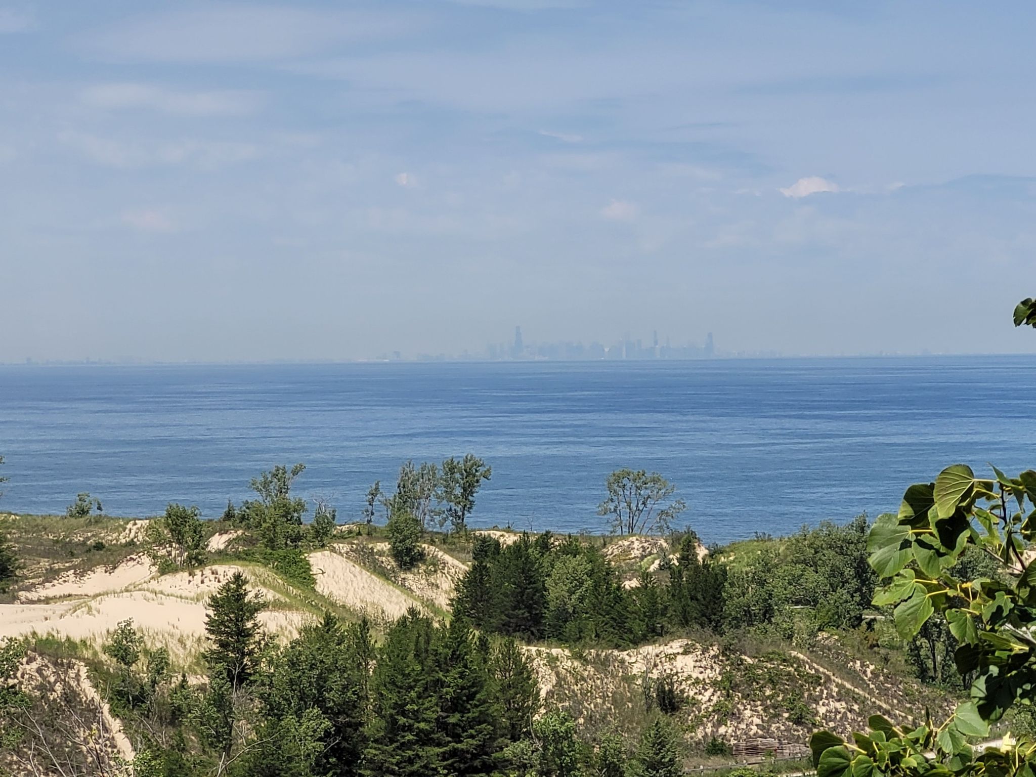 Distant city skyline over a large body of water, seen from sandy dunes. - West Beach 3-Loop Trail