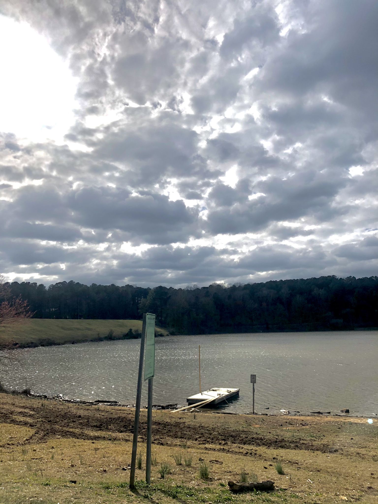 Small dock on a lake shore under a dramatic, cloudy sky. - Neuse River and Crabtree Creek Greenways Loop