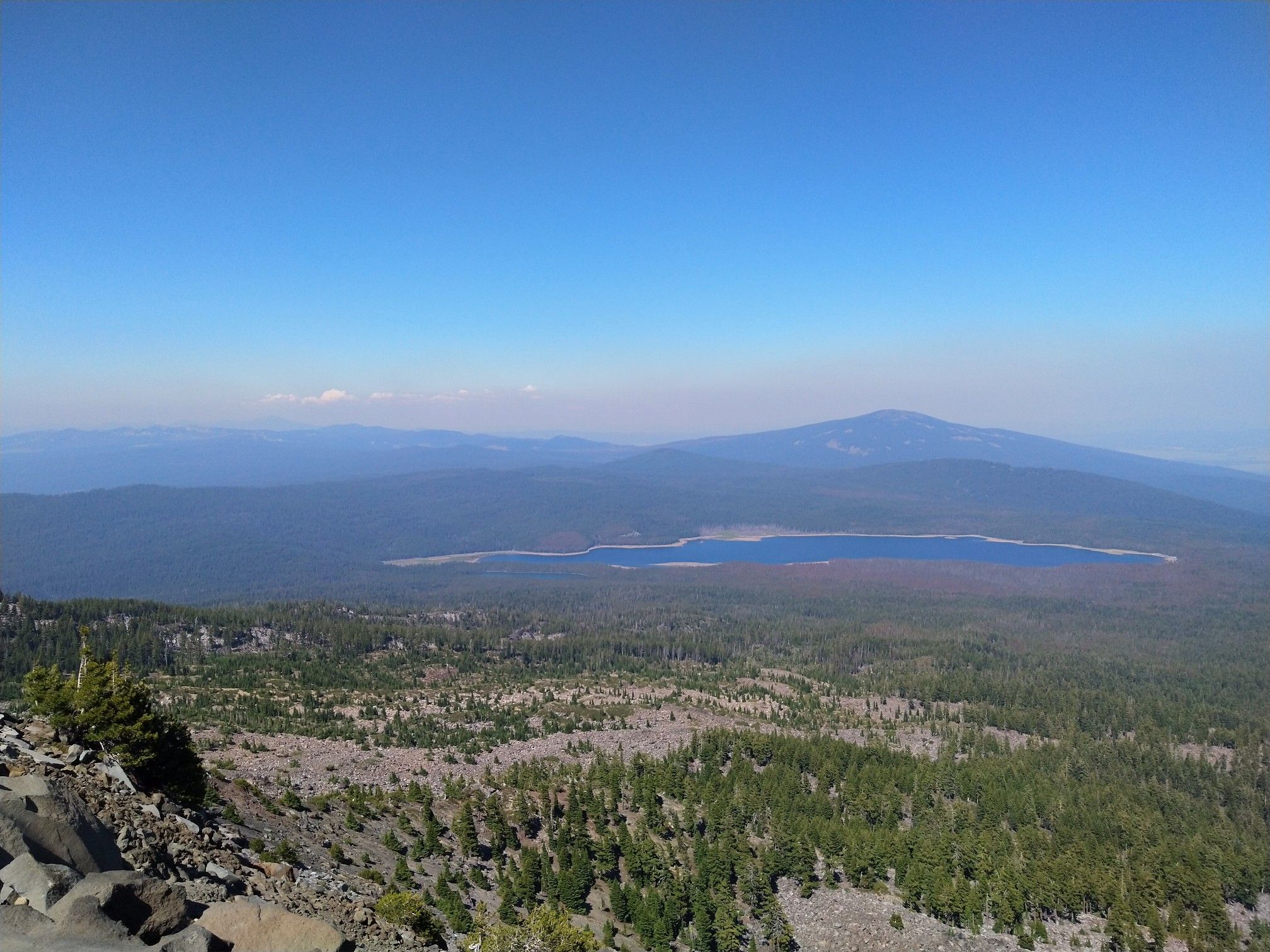 Expansive mountain landscape with a lake and dense forest under a blue sky. - Mount McLoughlin – Junction to Frey Lake loop from Mt. McLoughlin Trailhead