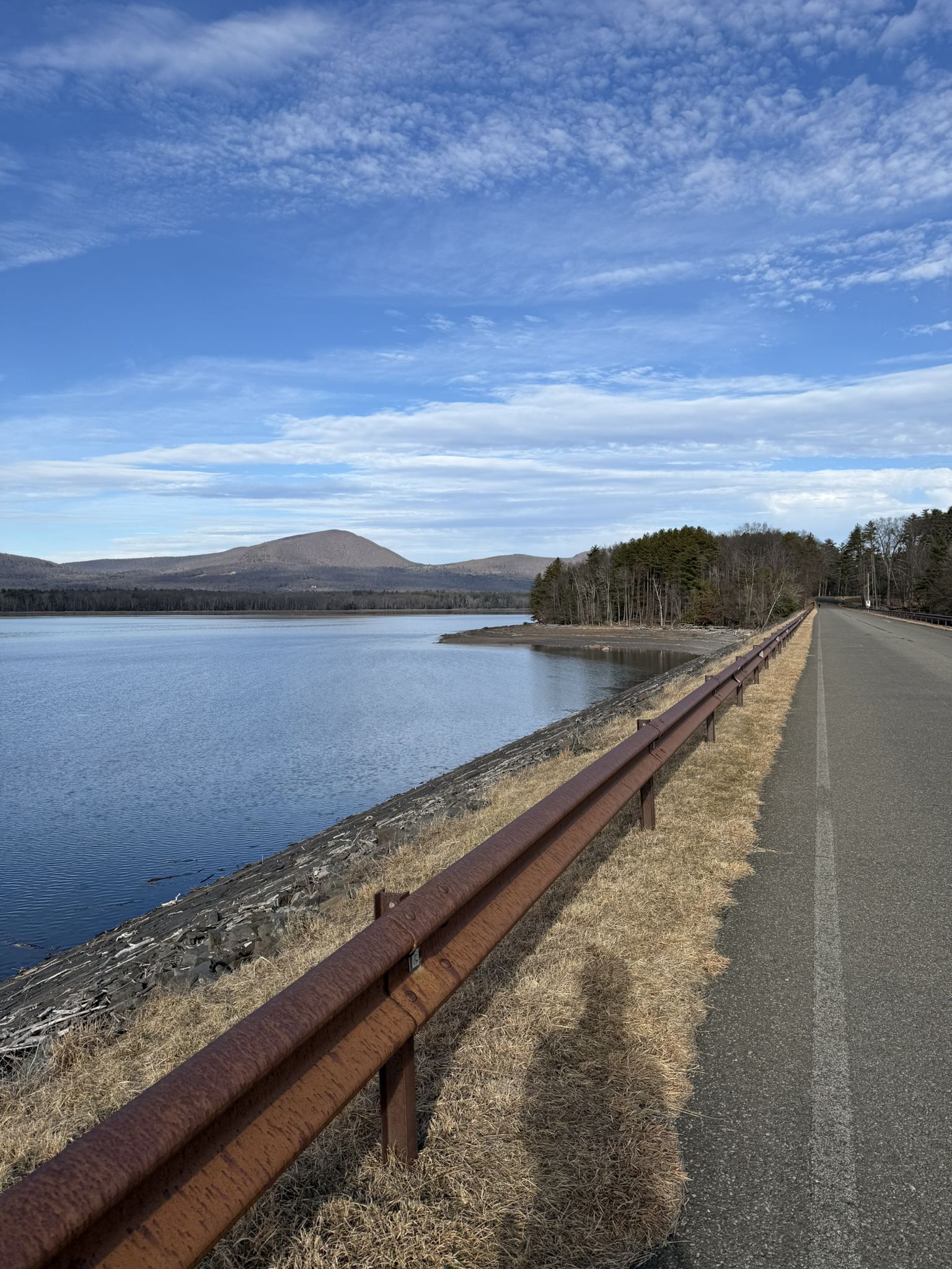 Paved road beside a lake with distant mountains under a blue sky. - Upper Ashokan Reservoir – Ashokan Reservoir loop from Boiceville