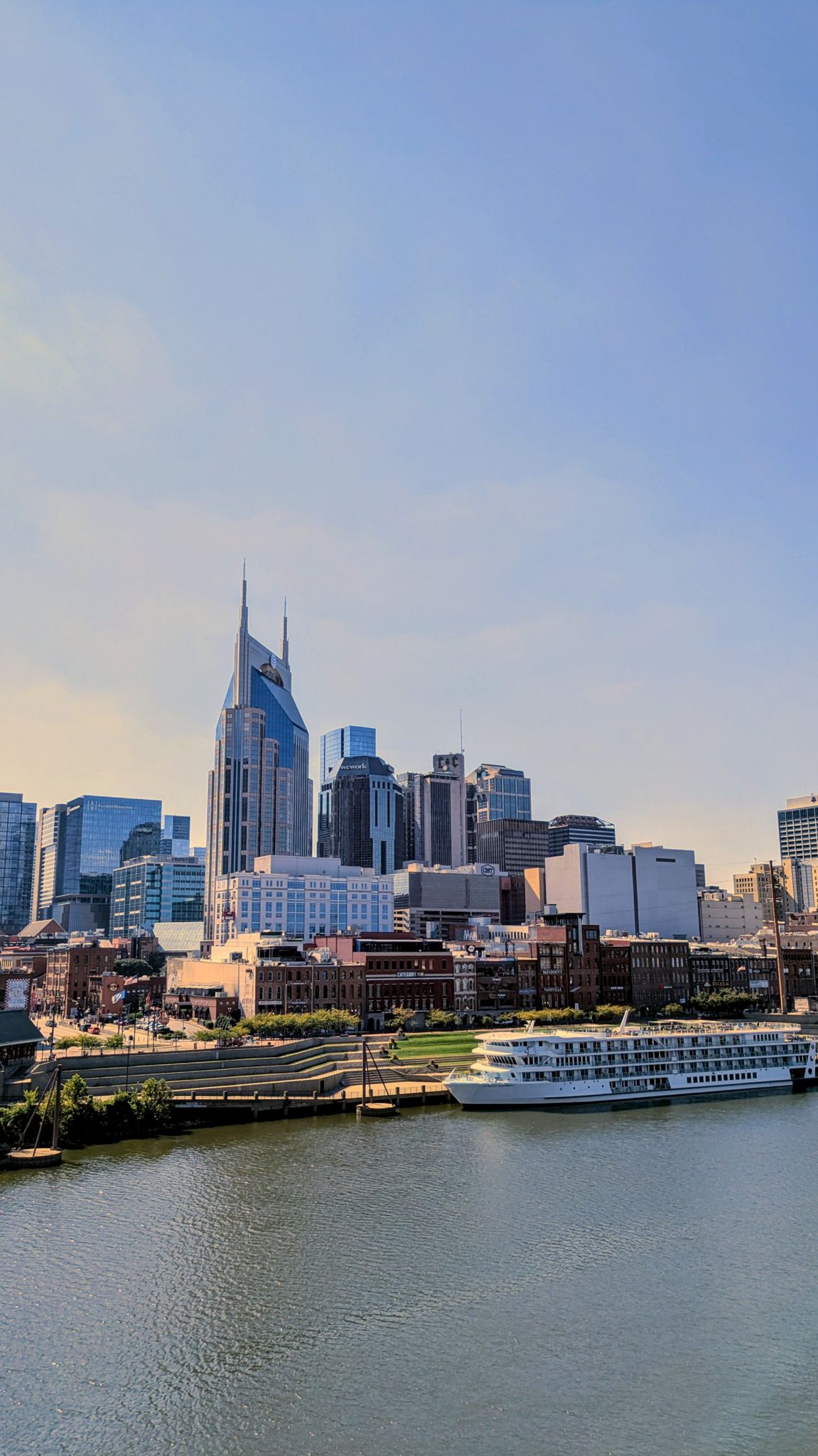 City skyline with a spired building, river, and a large docked boat. - Walk of Fame Park – Johnny Cash Museum  🎸 loop from Berry Hill