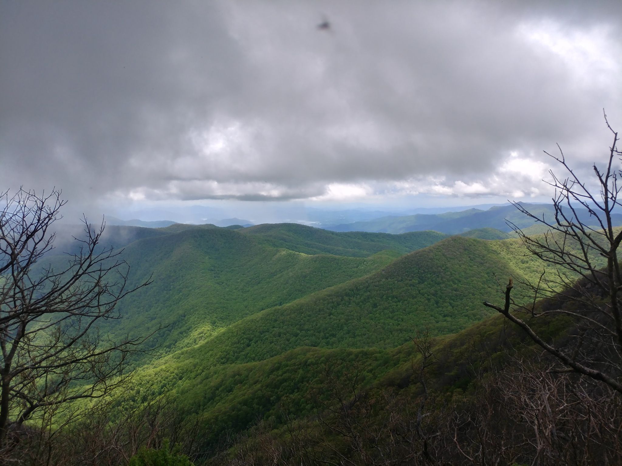 Green forested mountains under a dramatic cloudy sky with patches of light. - Standing Indian Mountain via Deep Gap