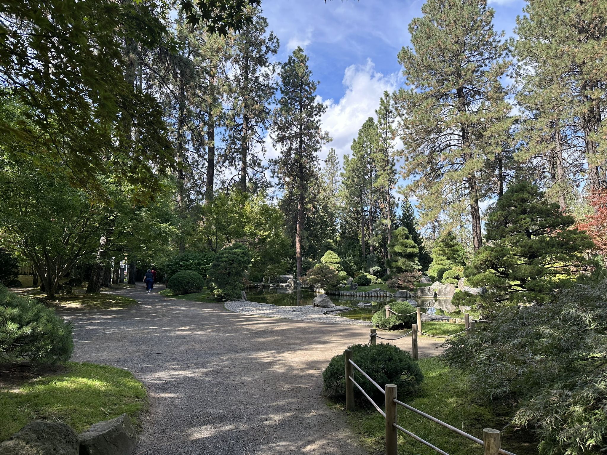 Gravel path through a serene garden with tall trees and manicured shrubs. - Manito and Cannon Hill Park Loop
