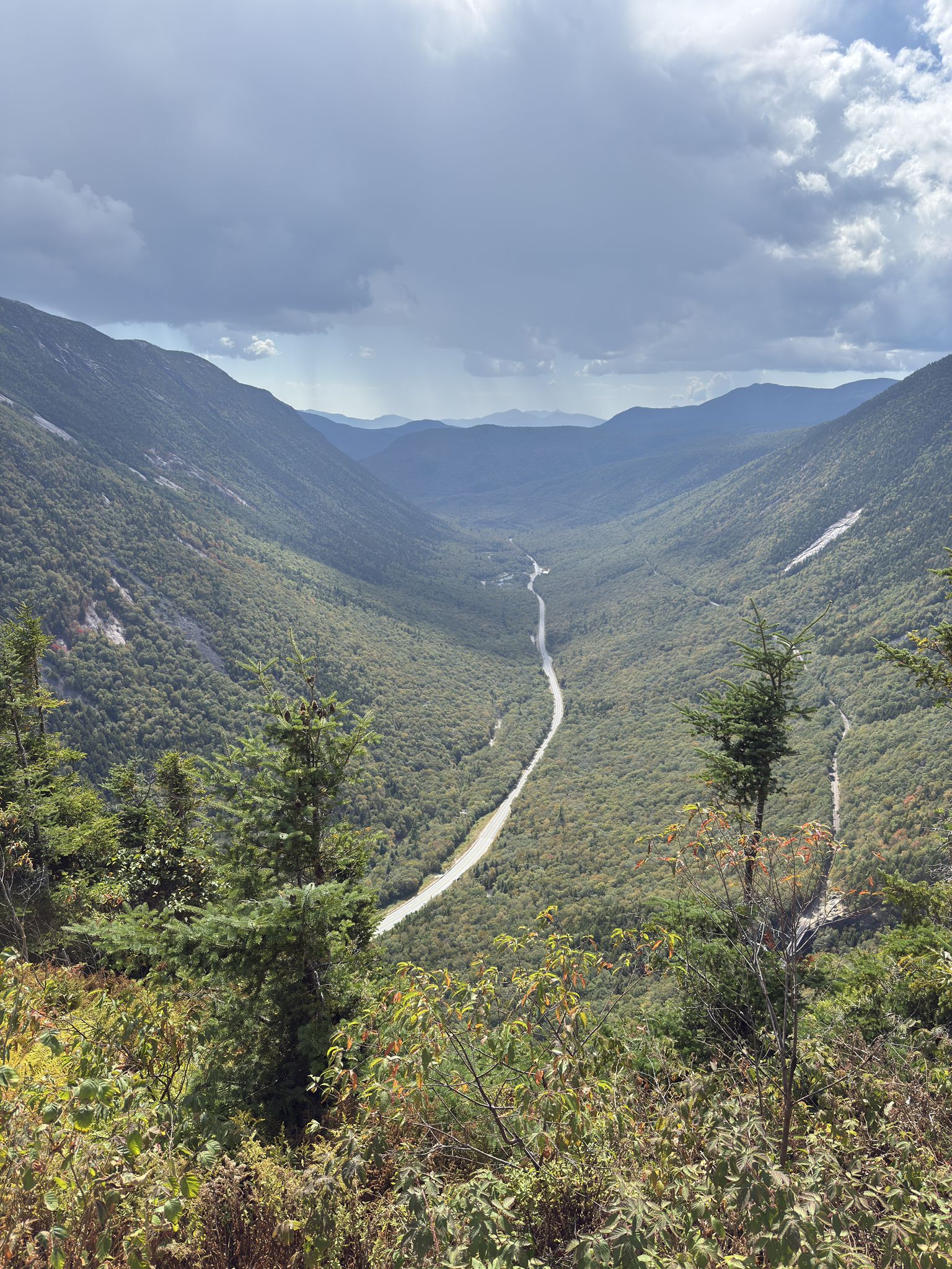Mountain valley with a winding road, lush green slopes, and cloudy sky. - Mount Willard Trail