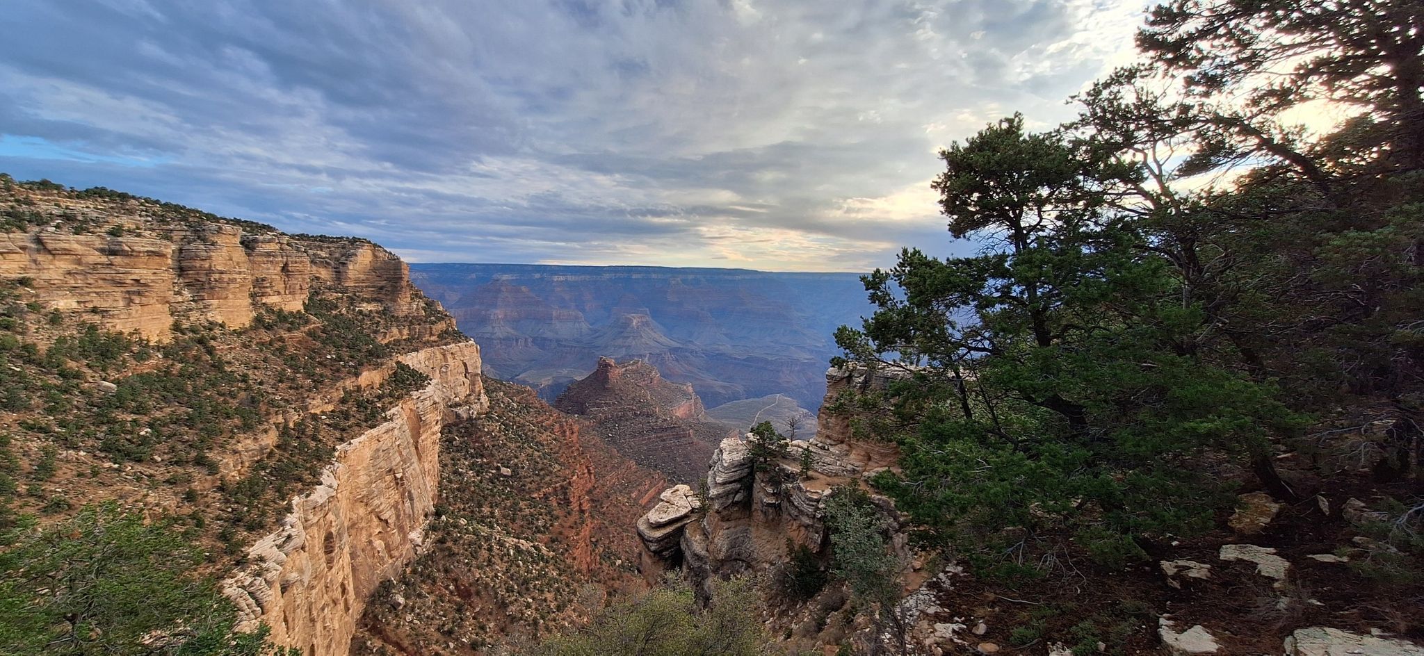 Wide canyon vista with dramatic clouds and trees on the right. - Bright Angel Trailhead – Hopi Point viewpoint loop from Grand Canyon Village