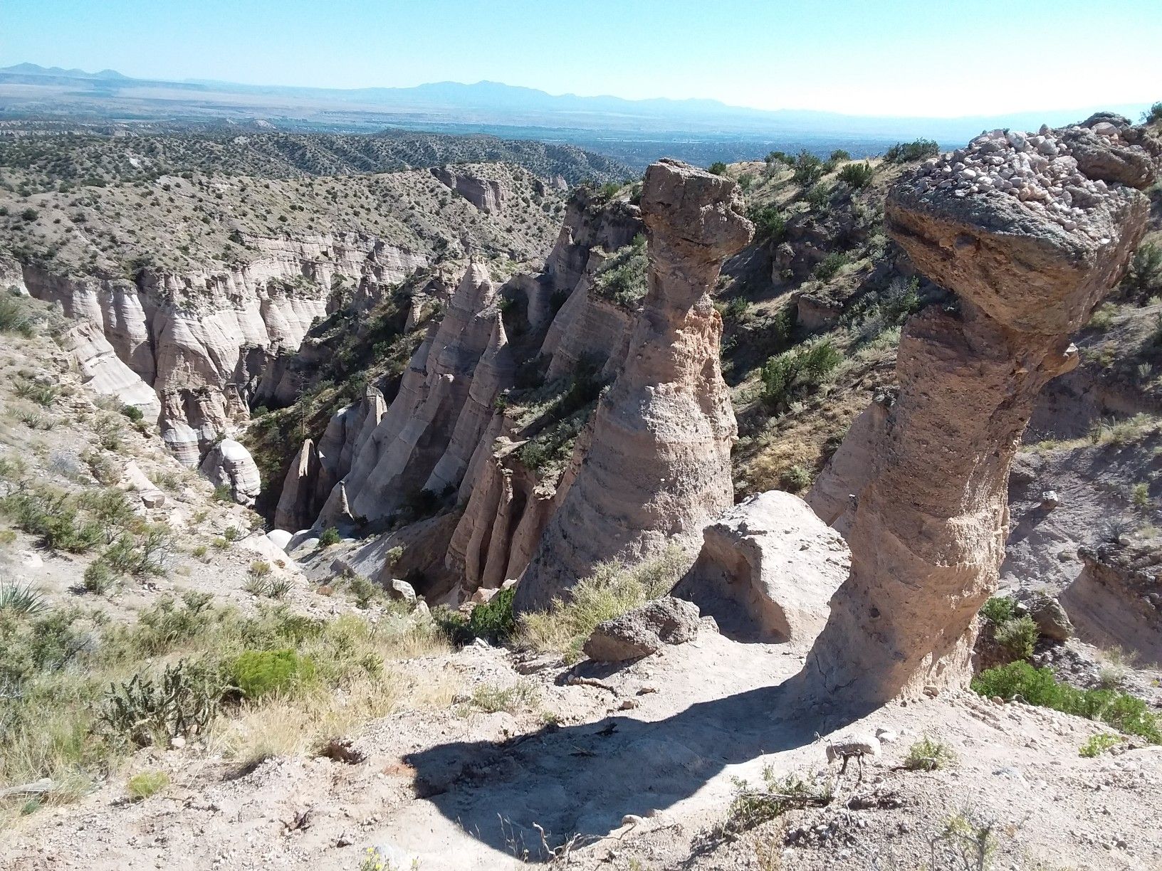 Two prominent hoodoos overlook a vast canyon under a clear sky. - Slot Canyon and Cave Loop Trail