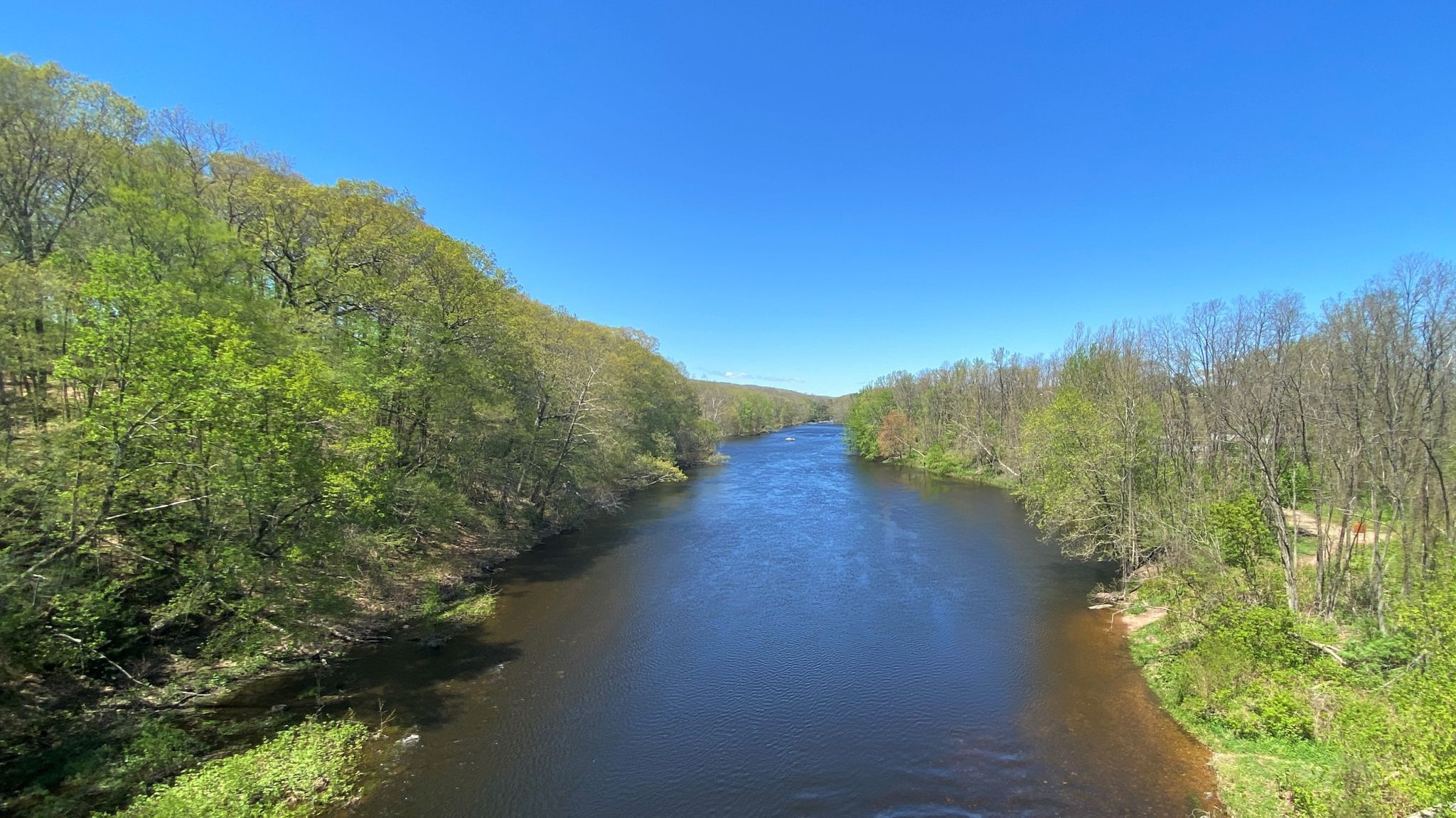 River flows through a lush green valley under a clear, bright blue sky. - Farmington River Bridge – East Coast Greenway loop from Town Open Space (Sanford Drive)
