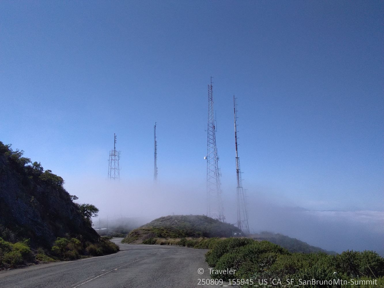 Communication towers emerging from dense fog on a hillside road. - San Bruno Mountain – San Bruno Views loop from San Bruno Mountain State and County Park