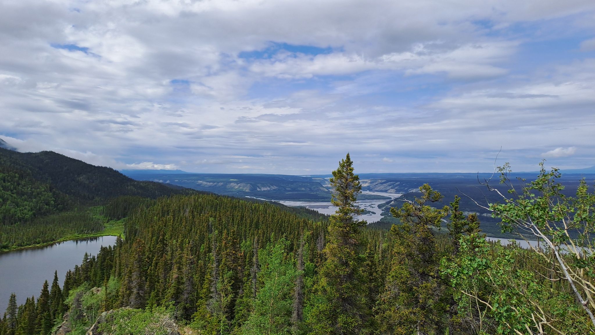 Panoramic view of a mountain lake, dense forest, and distant river under cloudy skies. - Liberty Falls Trail
