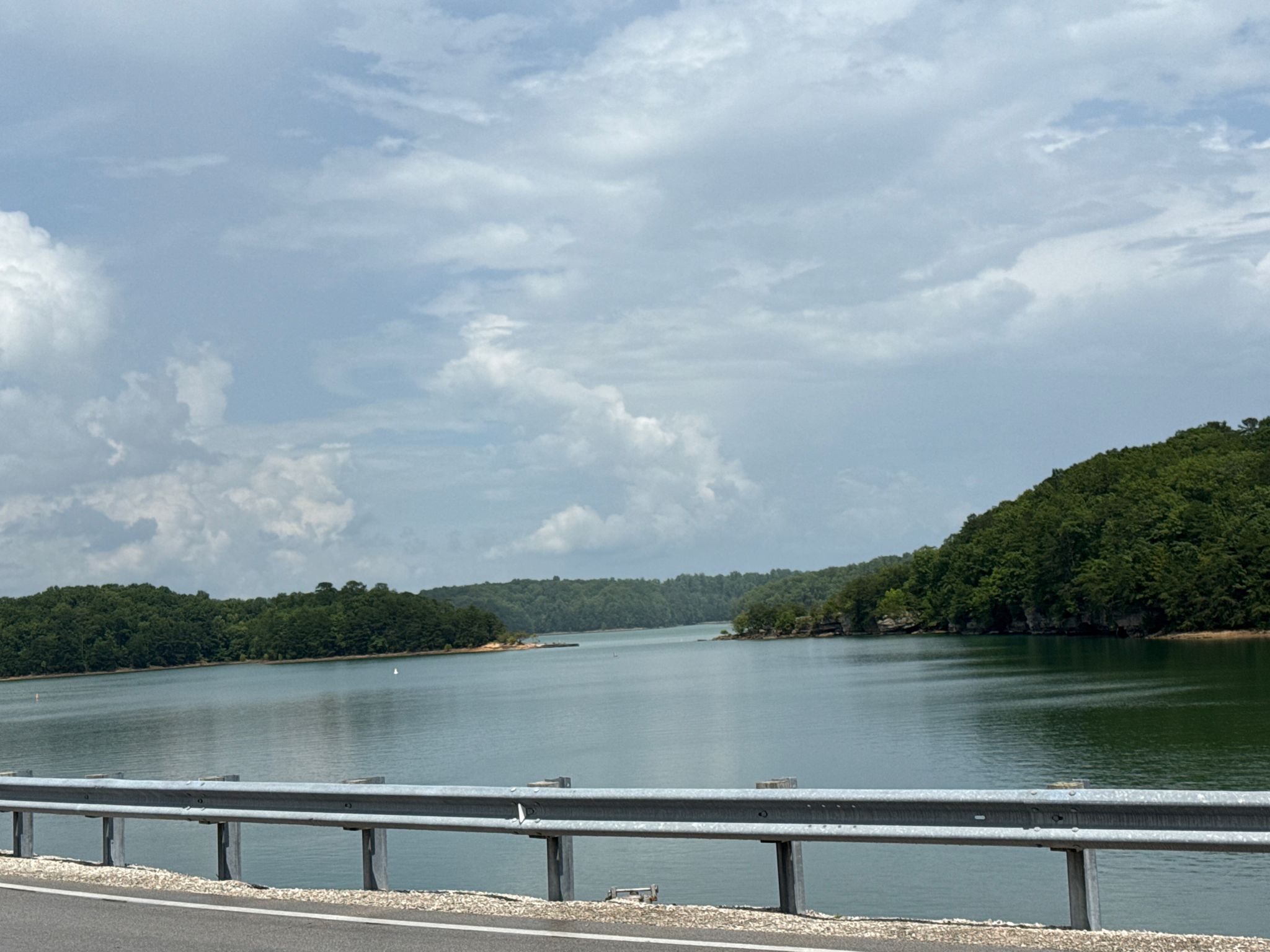 Wide lake with forested shores under a cloudy sky, viewed from a road. - Sheltowee Trace NRT: Section 26 "Laurel Lake"