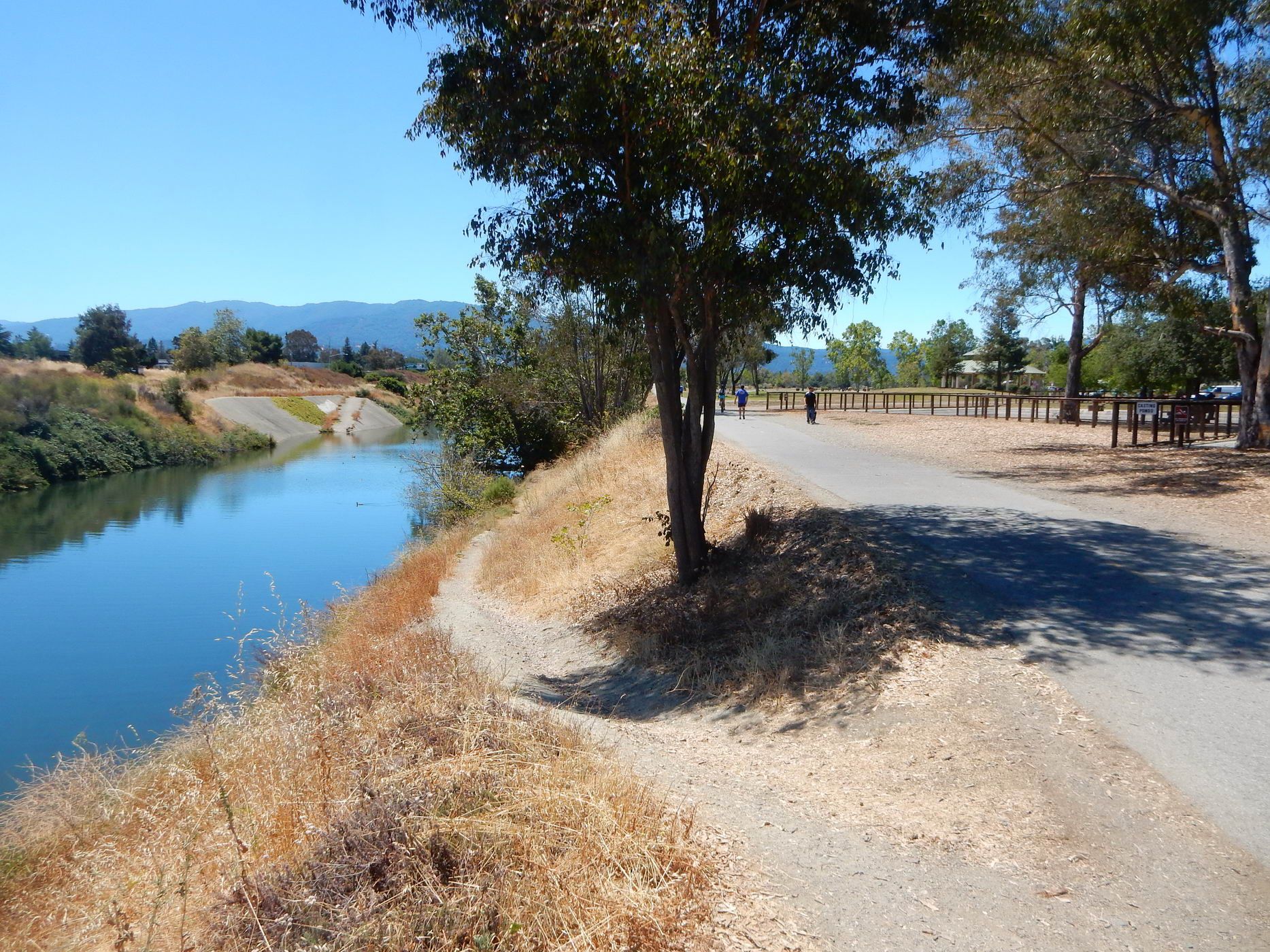 Paved path next to a canal, people walking in the distance. - Fly Casting Pond loop from Campbell