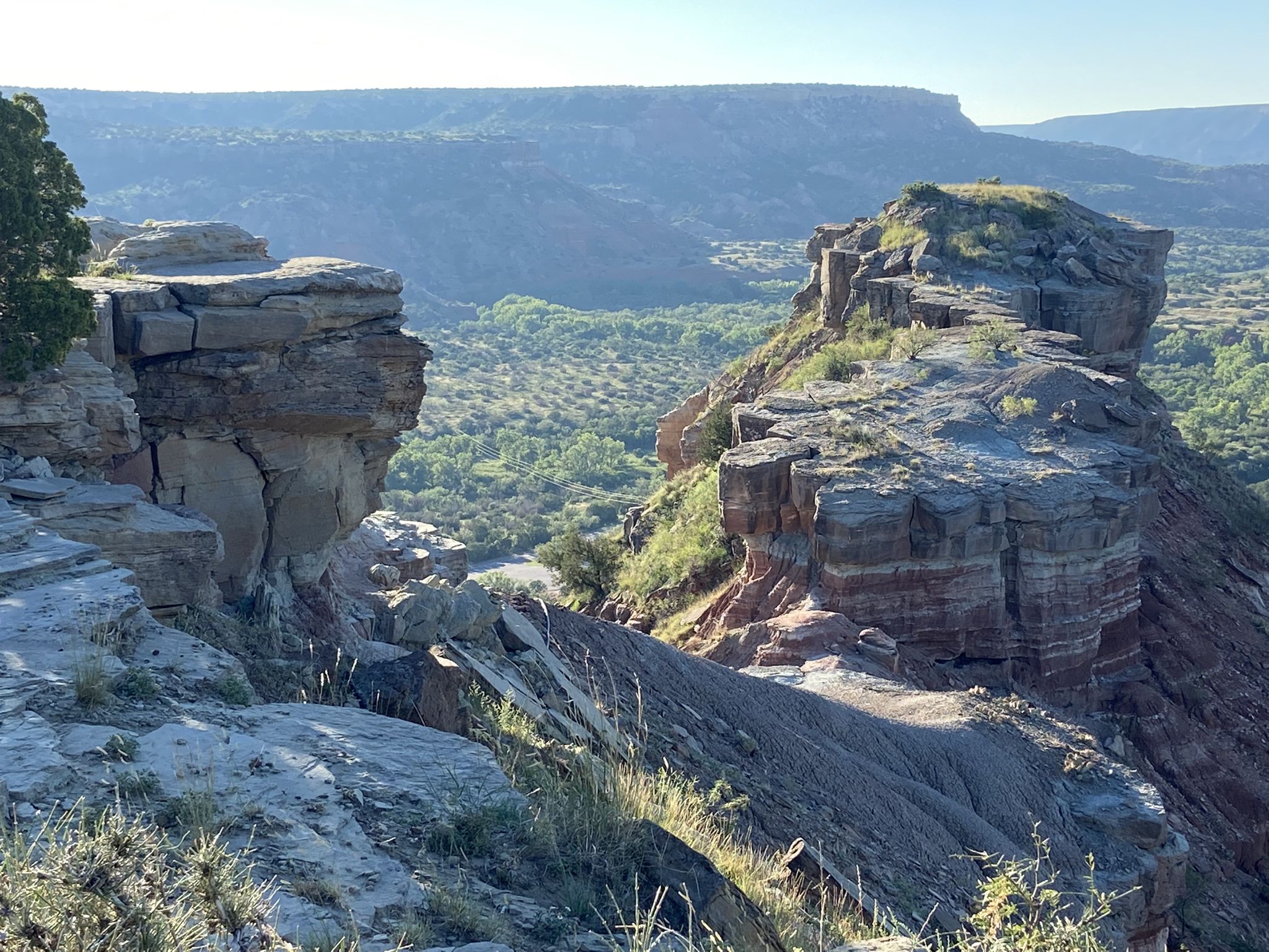 Rocky canyon landscape with green valley below under bright daylight. - CCC Trail