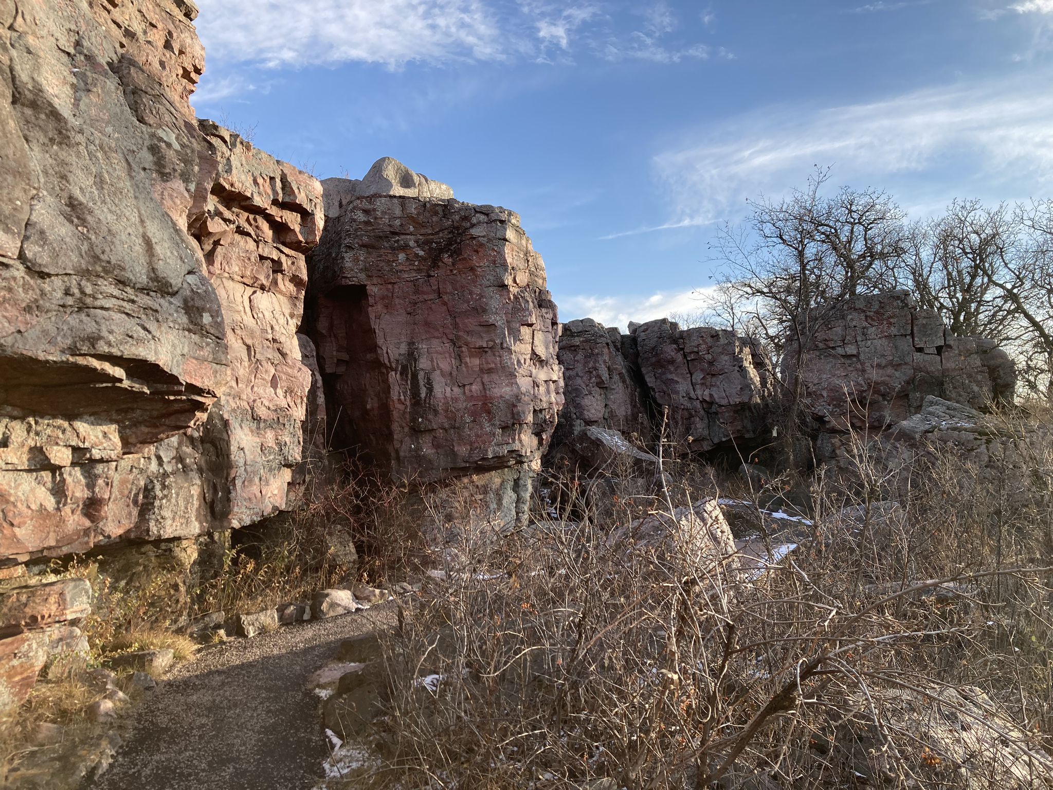 Rocky path winding past massive red rock formations and dry brush. - Circle Trail