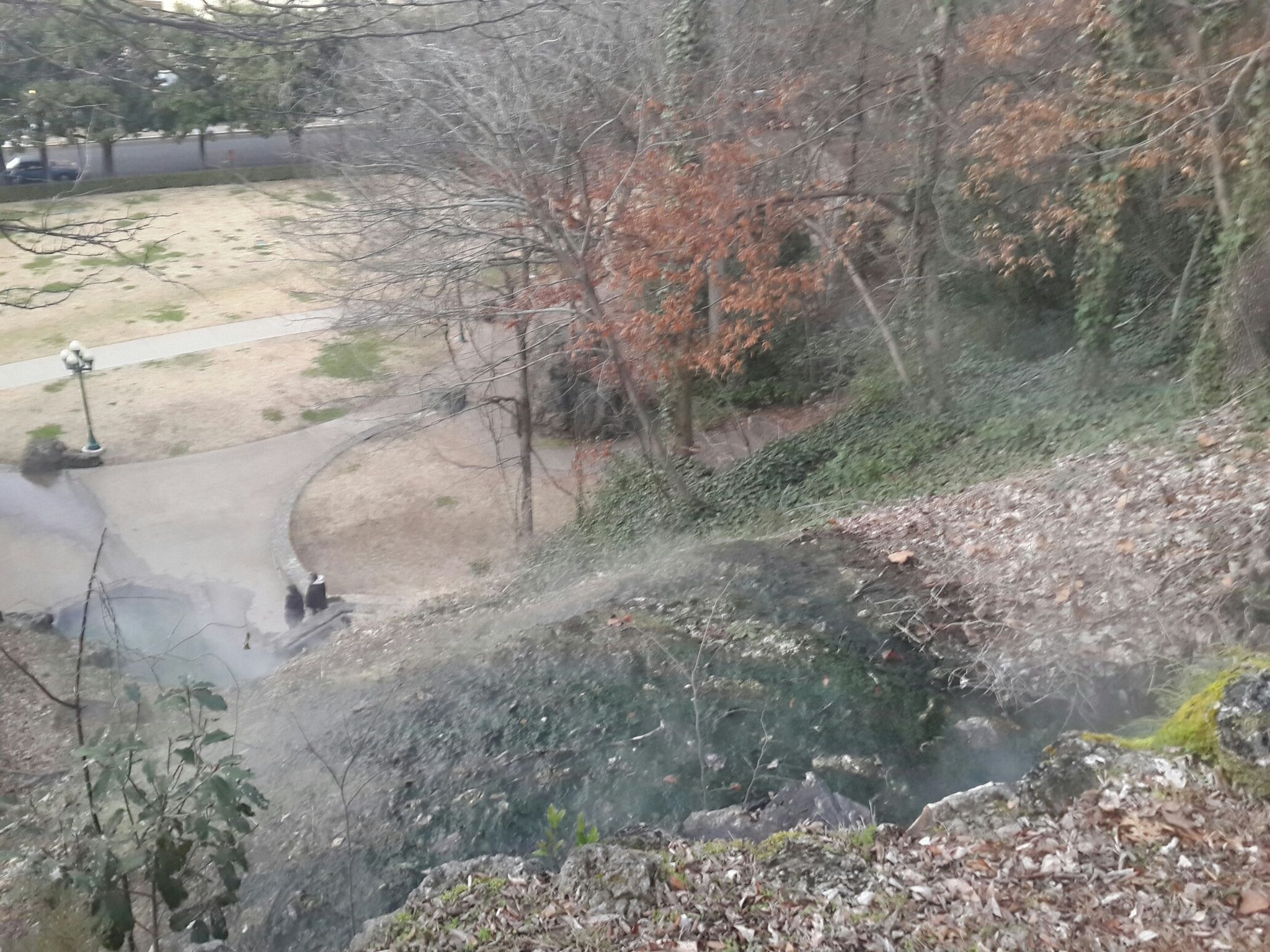 Overlook of a wooded hillside with a path and two people below. - Hot Springs Mountain and North Mountain Loop
