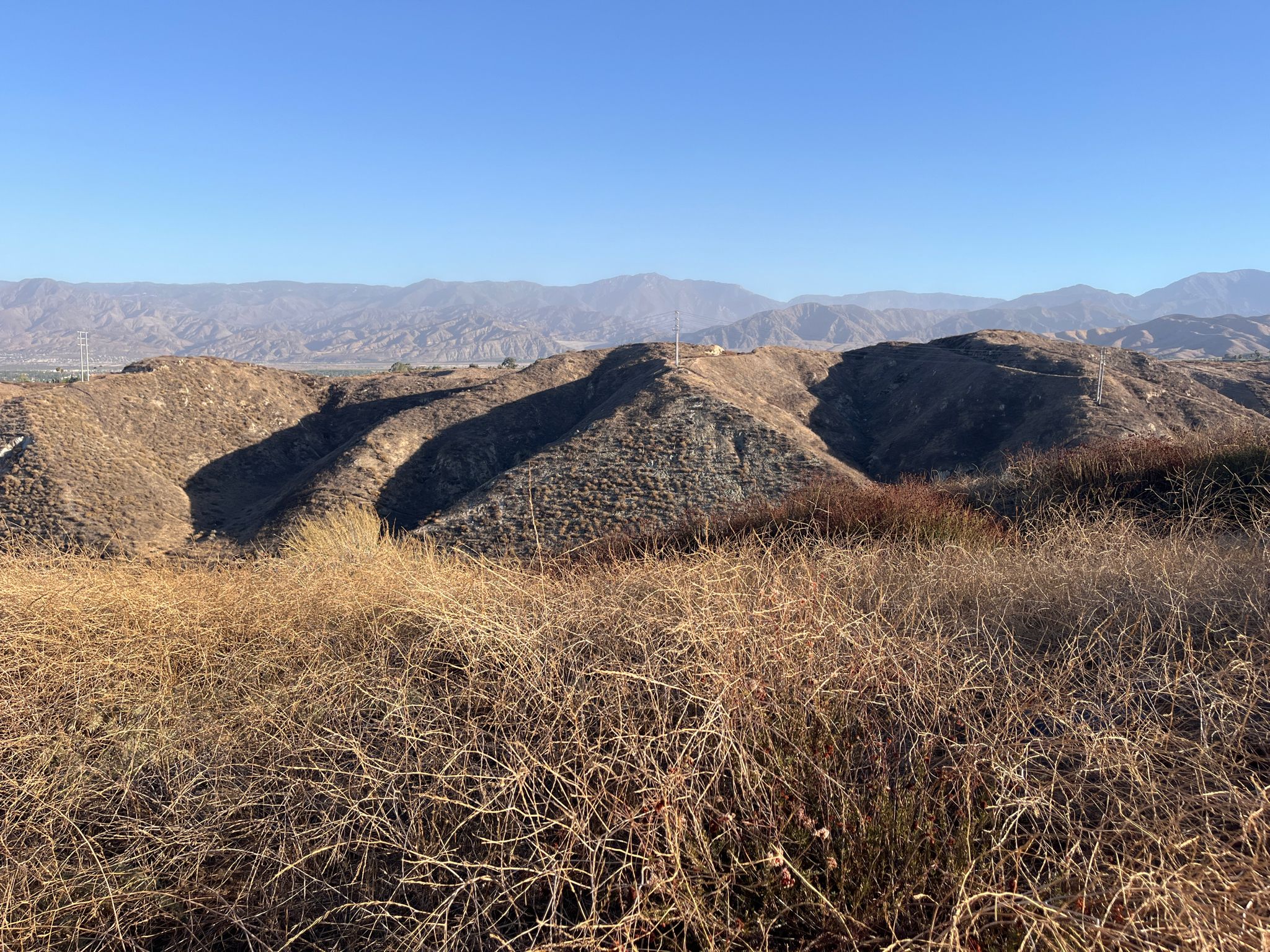 Dry golden grass in foreground with rolling brown hills and distant mountains. - Panorama Point – Caroline Park loop from Herngt Aki Reserve