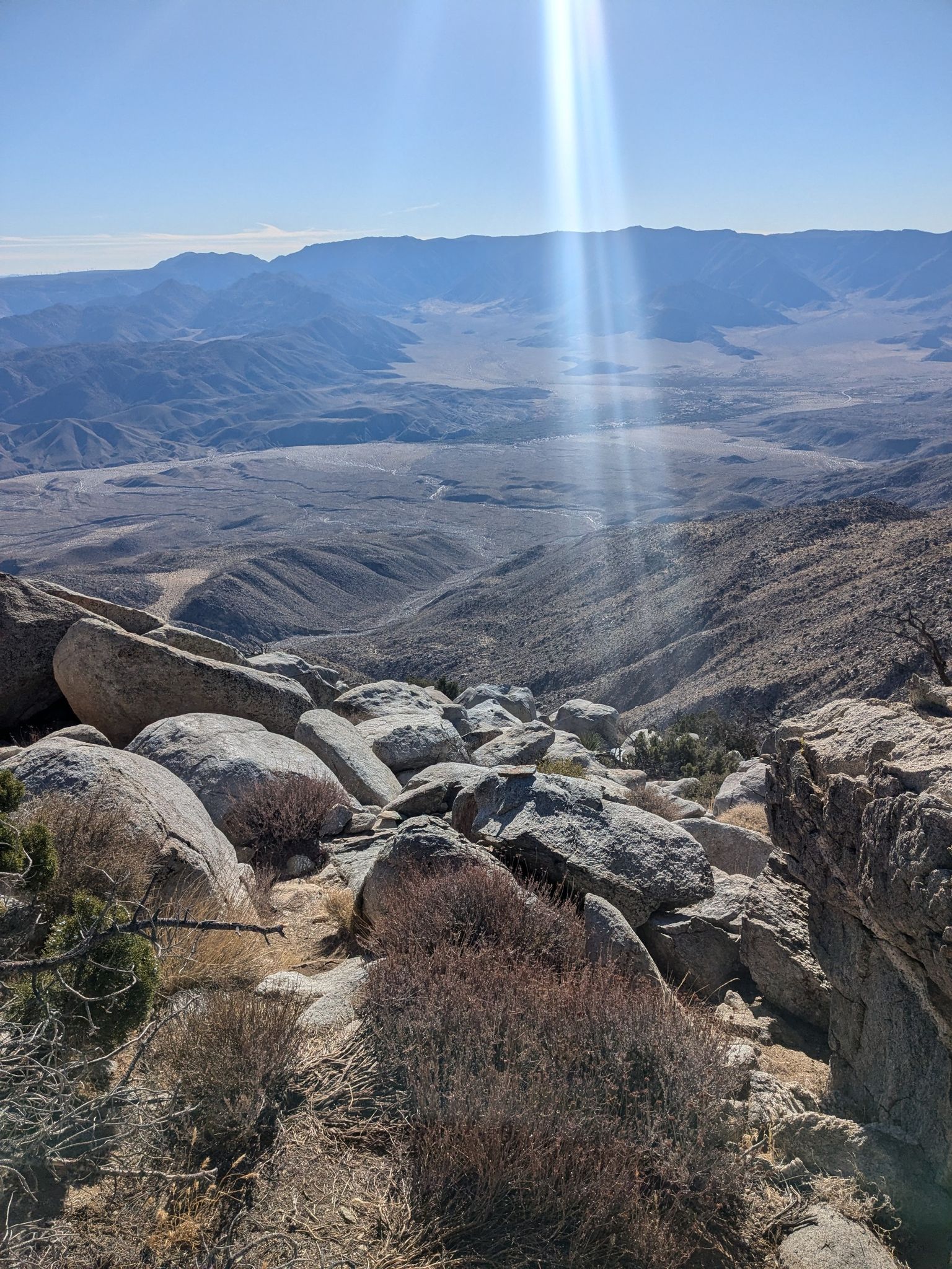 Panoramic desert valley view from a rocky peak with bright sun flare. - Whale Peak Trail
