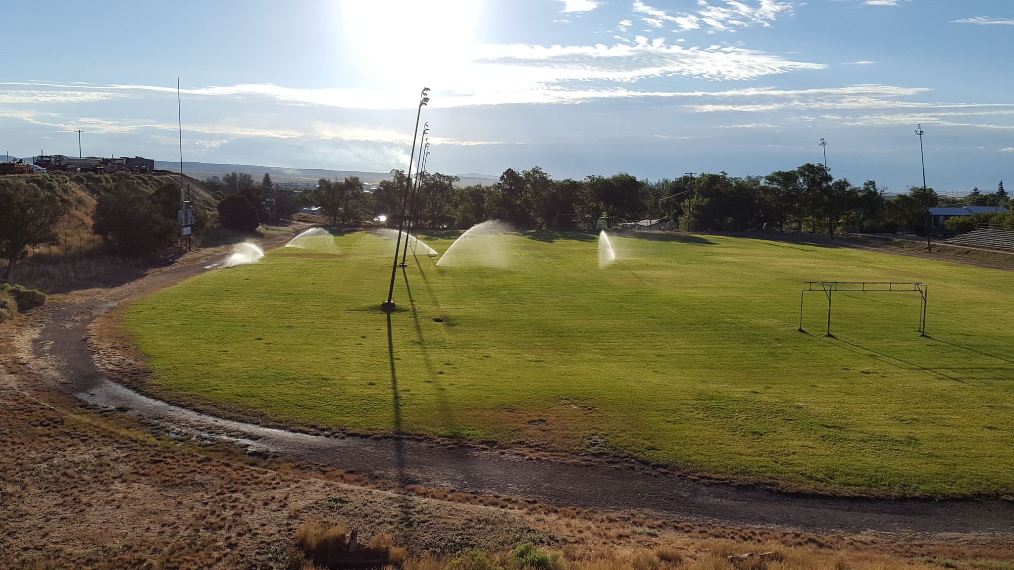 Sunny day over a green field being watered by multiple sprinklers. - Rawlins Continental Divide Trail Loop