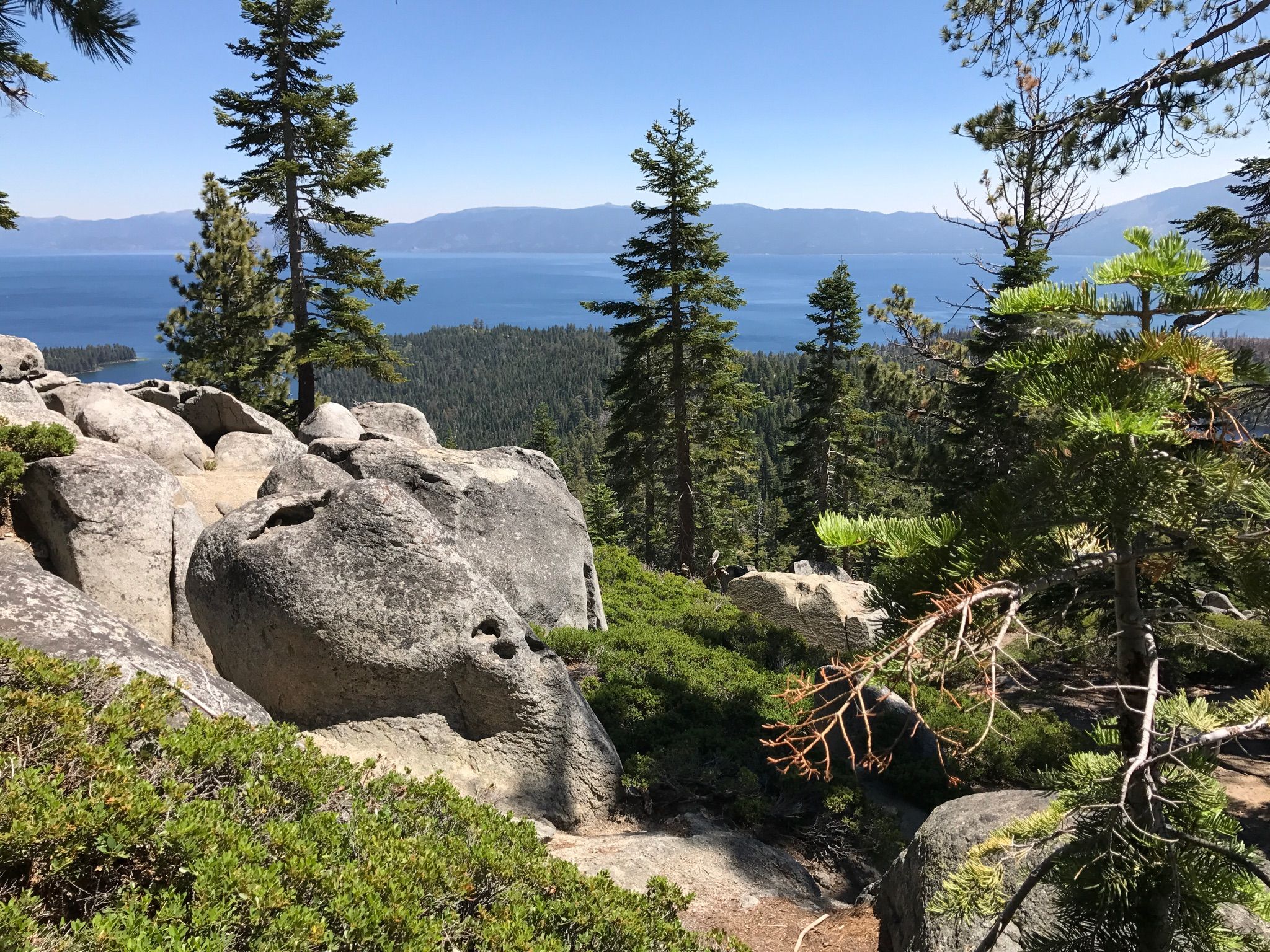 Rocky foreground, pine trees, and a large blue lake under a clear sky. - Bayview and Eagle Lake Trail Loop
