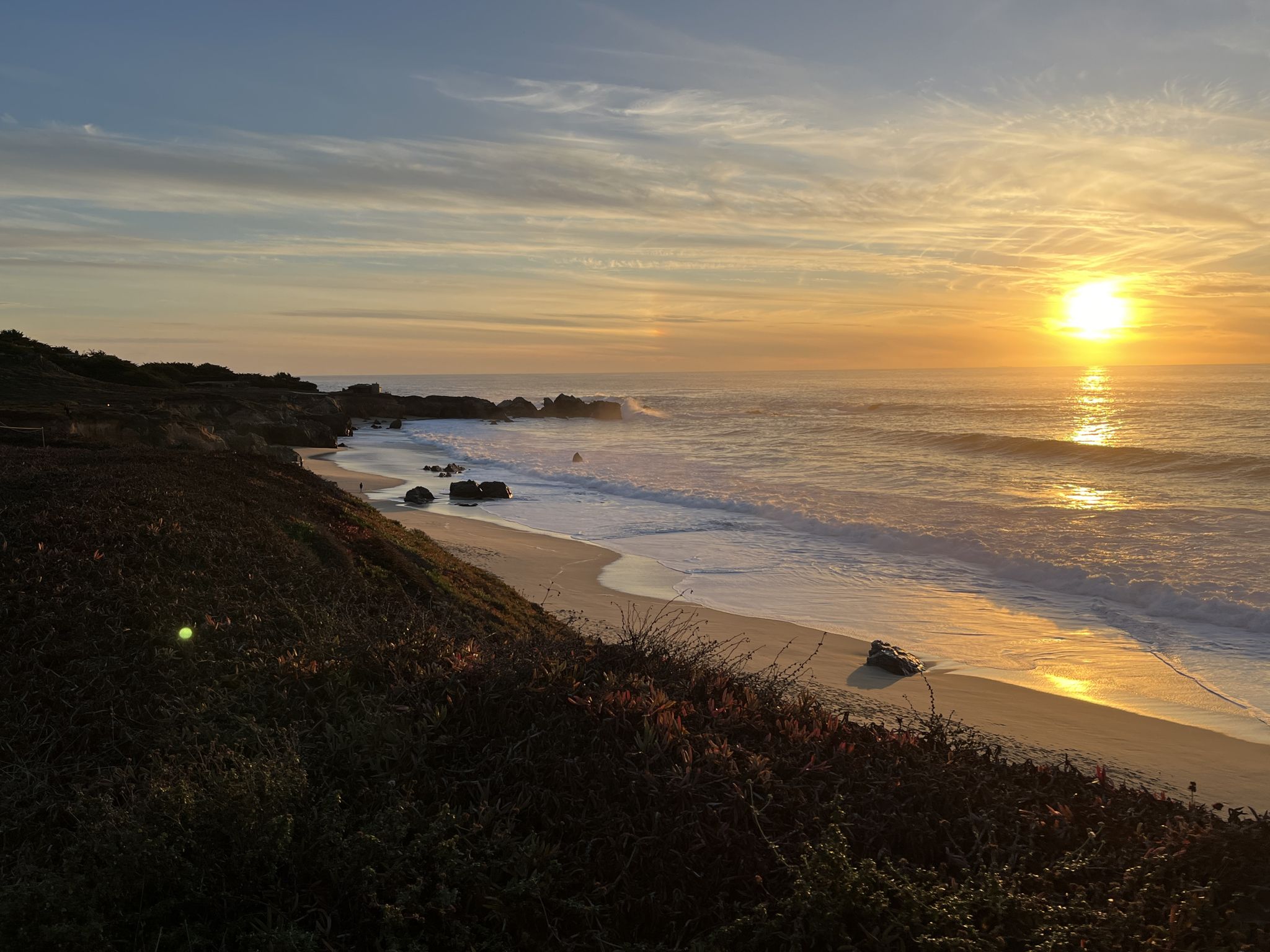 Golden sunset over a sandy beach with waves crashing on the rocky coast. - Calla Lily Valley Trail