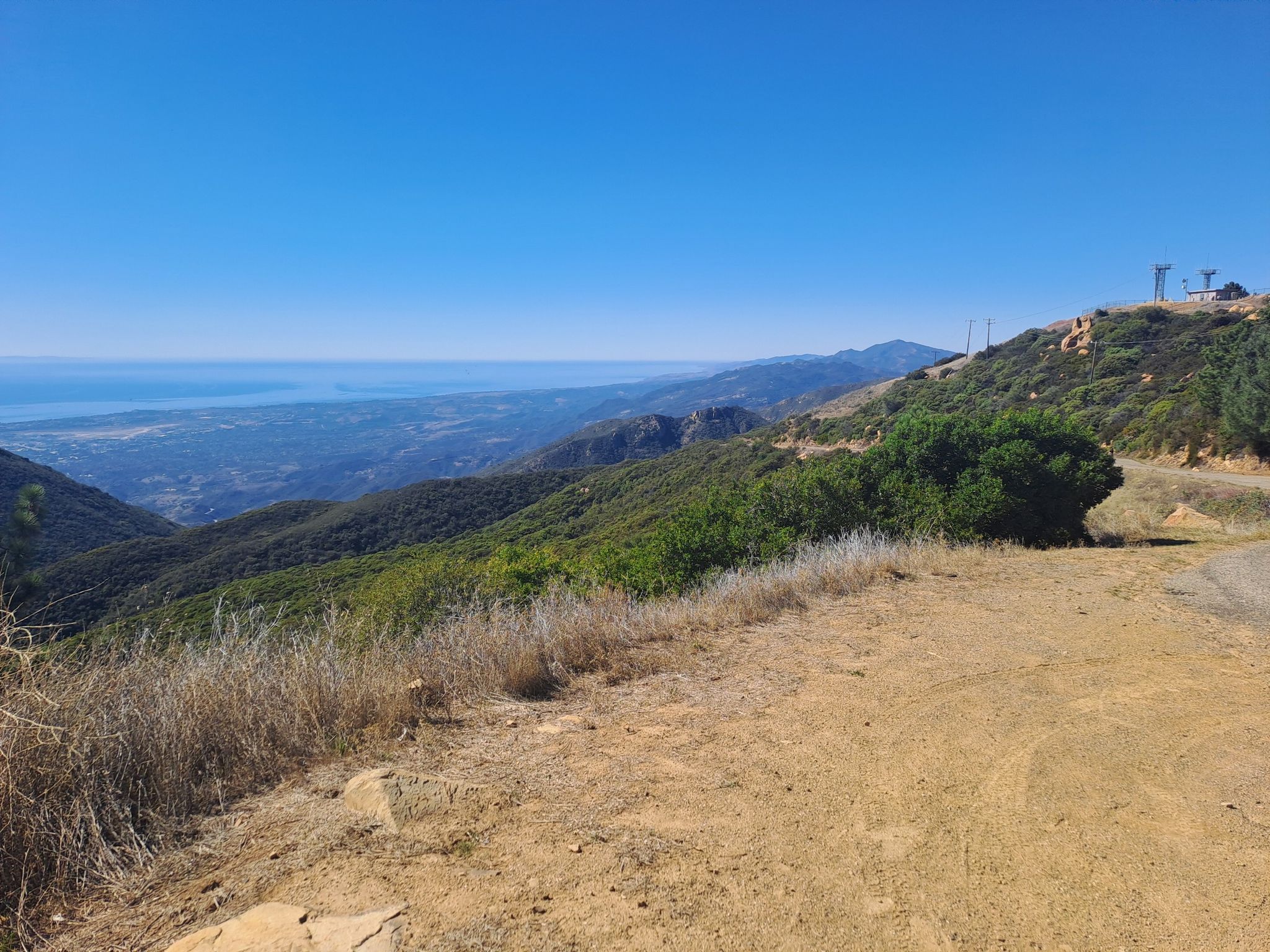 Sunny view of a dirt path winding through green and dry hills. - La Cumbre Peak loop from Chumash Painted Cave State Historic Park