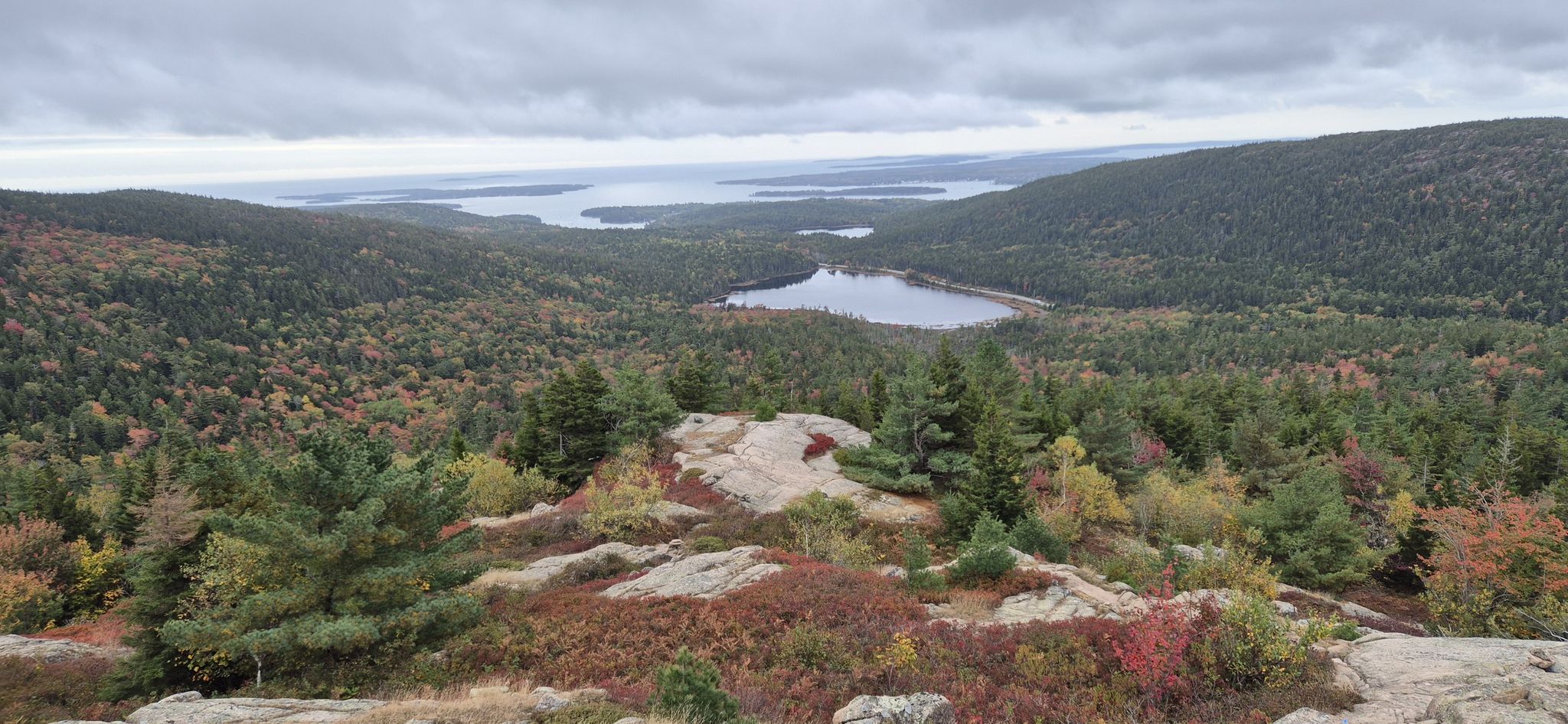 Overcast day, panoramic view of a lake and distant ocean surrounded by autumn forests. - Sargeant Mountain Ridge Loop