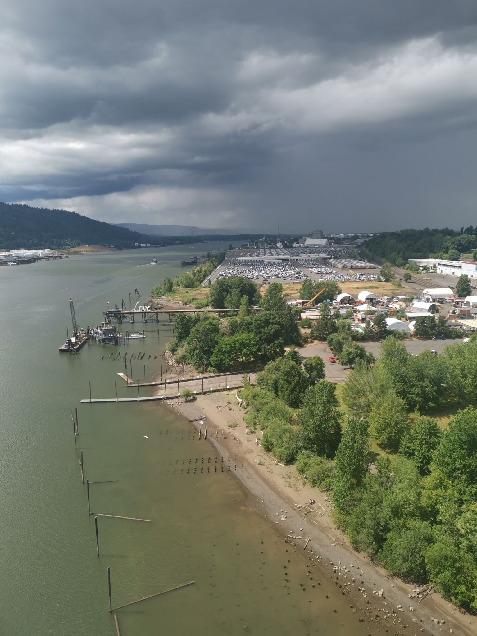 Aerial view of a river, sandy bank, and industrial area under a stormy sky. - Northwest Leif Erikson Drive – Leif Erikson Drive loop from Albina/Mississippi