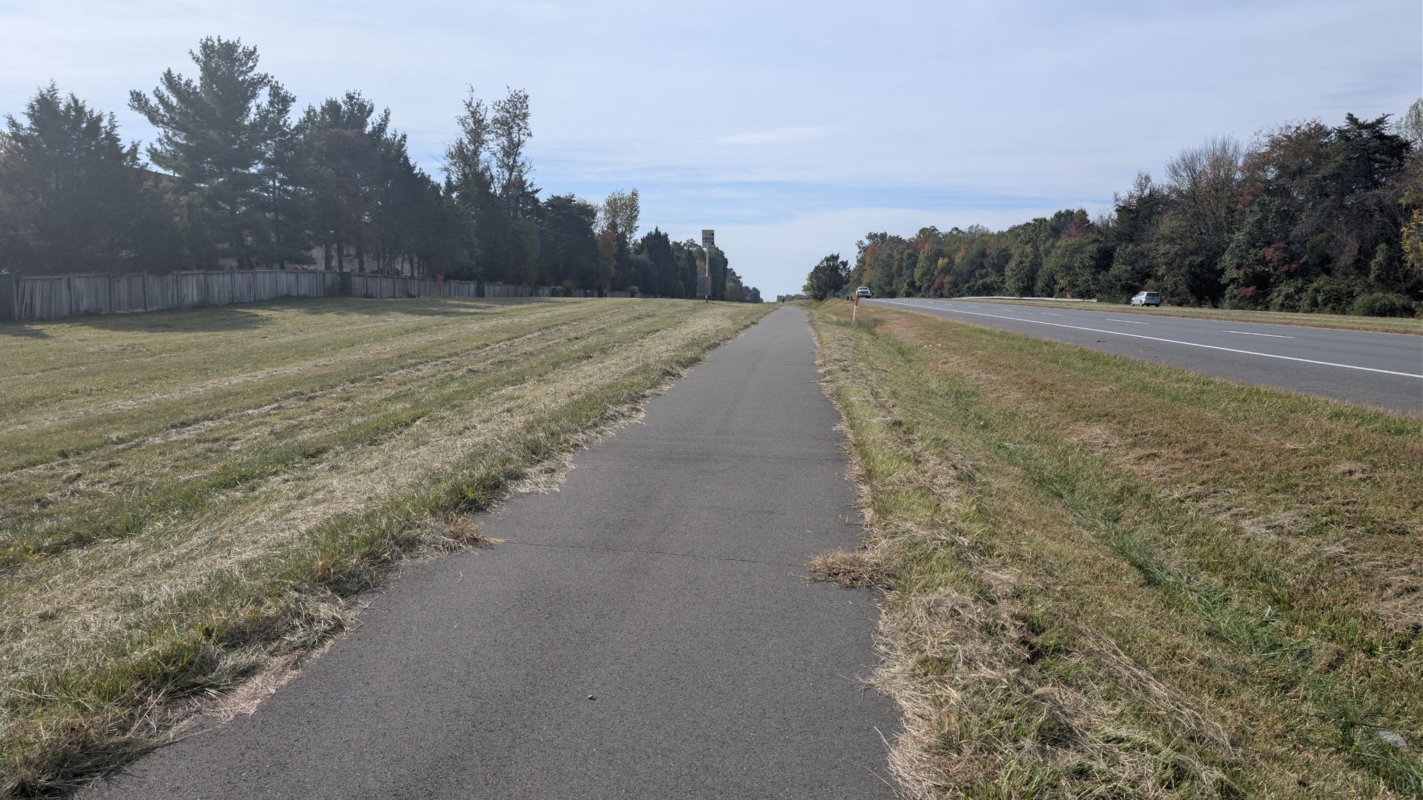 Paved path next to a highway and dry grassy field under a cloudy sky. - Running loop from Floris