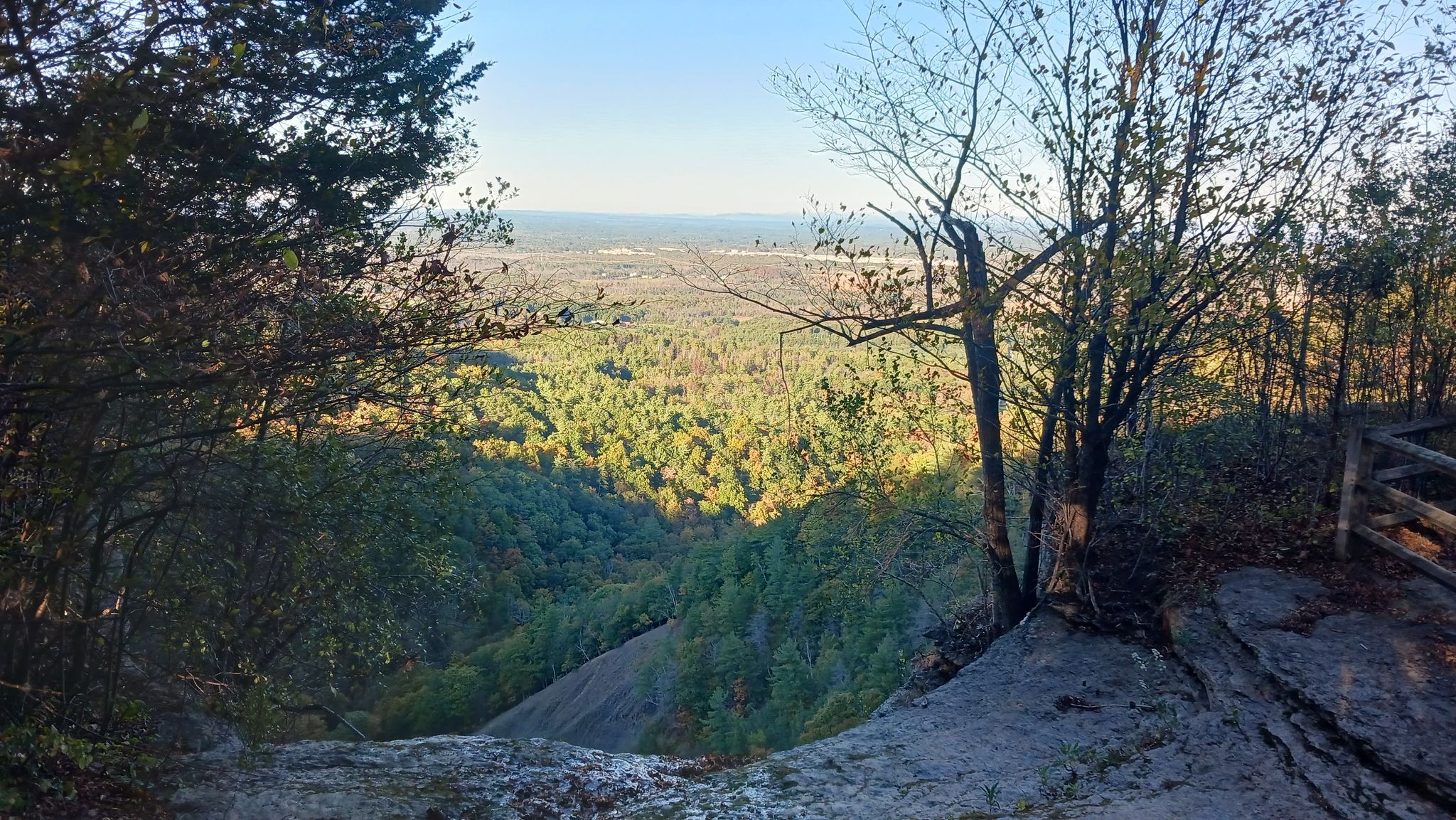 Golden hour view from a cliff overlooking a vast, autumn-colored forest. - Hiking trail along the cliffs – Waterfall at Thacher Park loop from future preserve