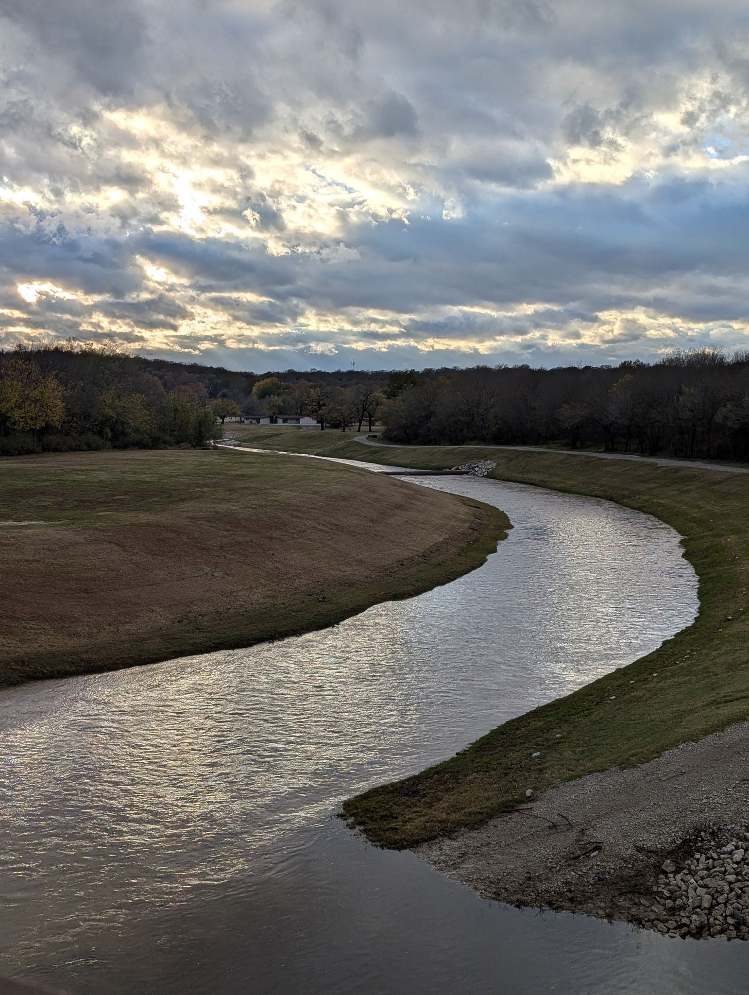 Winding river with grassy banks under a cloudy sky with bright light. - Osage Prairie Trail and Skiatook Lake Loop