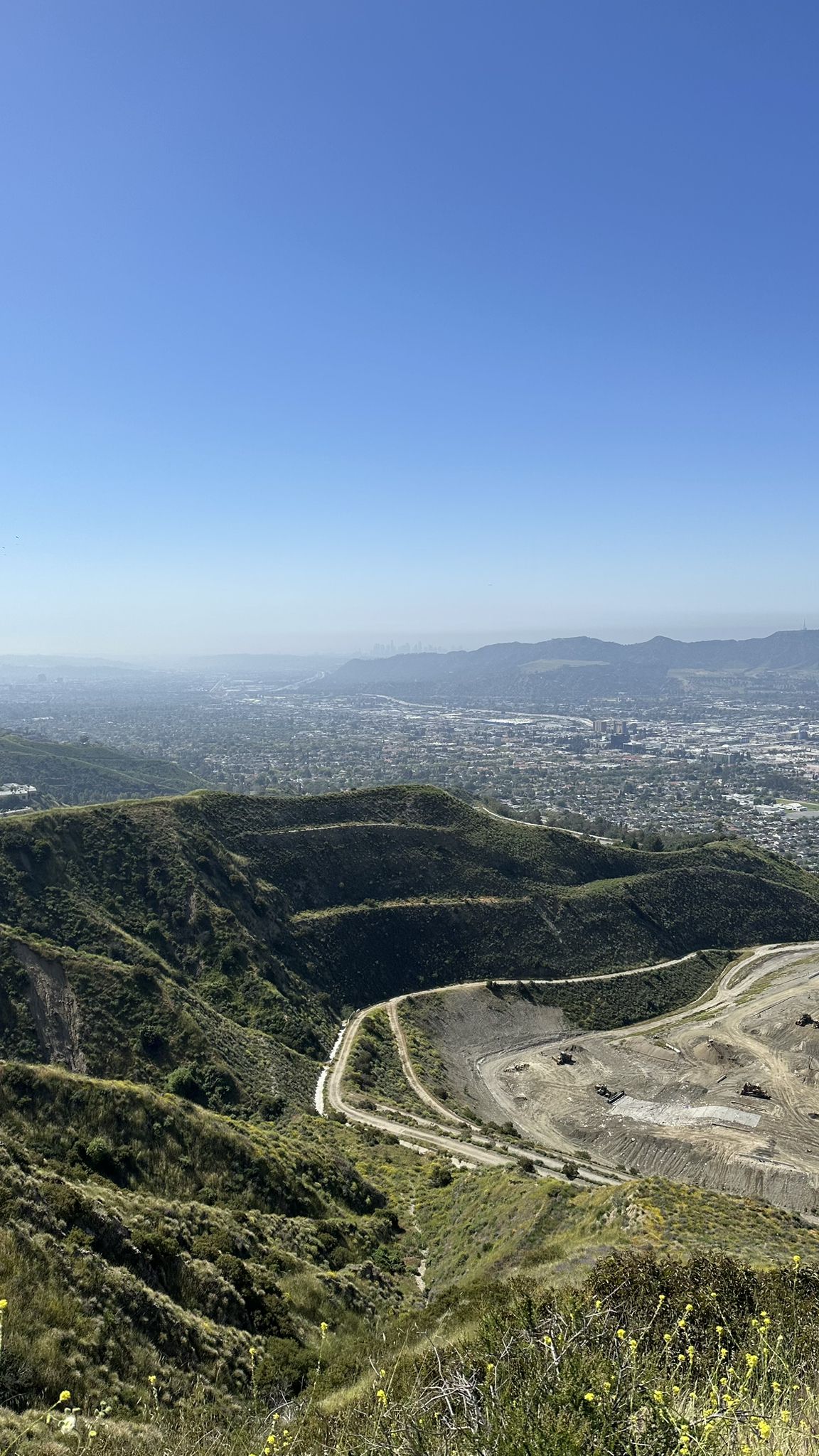 Panoramic view of green hills, a distant city, and clear blue sky. - Stough Canyon Loop Trail