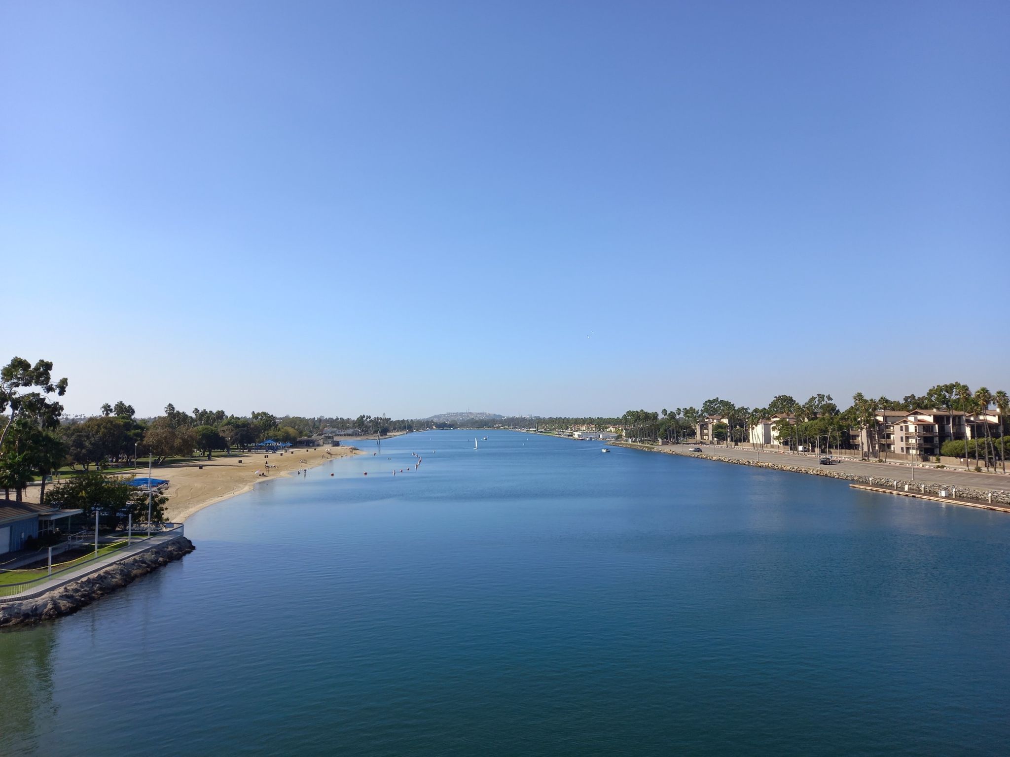 Wide river with sandy beaches, distant buildings, and clear blue sky. - Marine Stadium and Marina Pacifica Loop