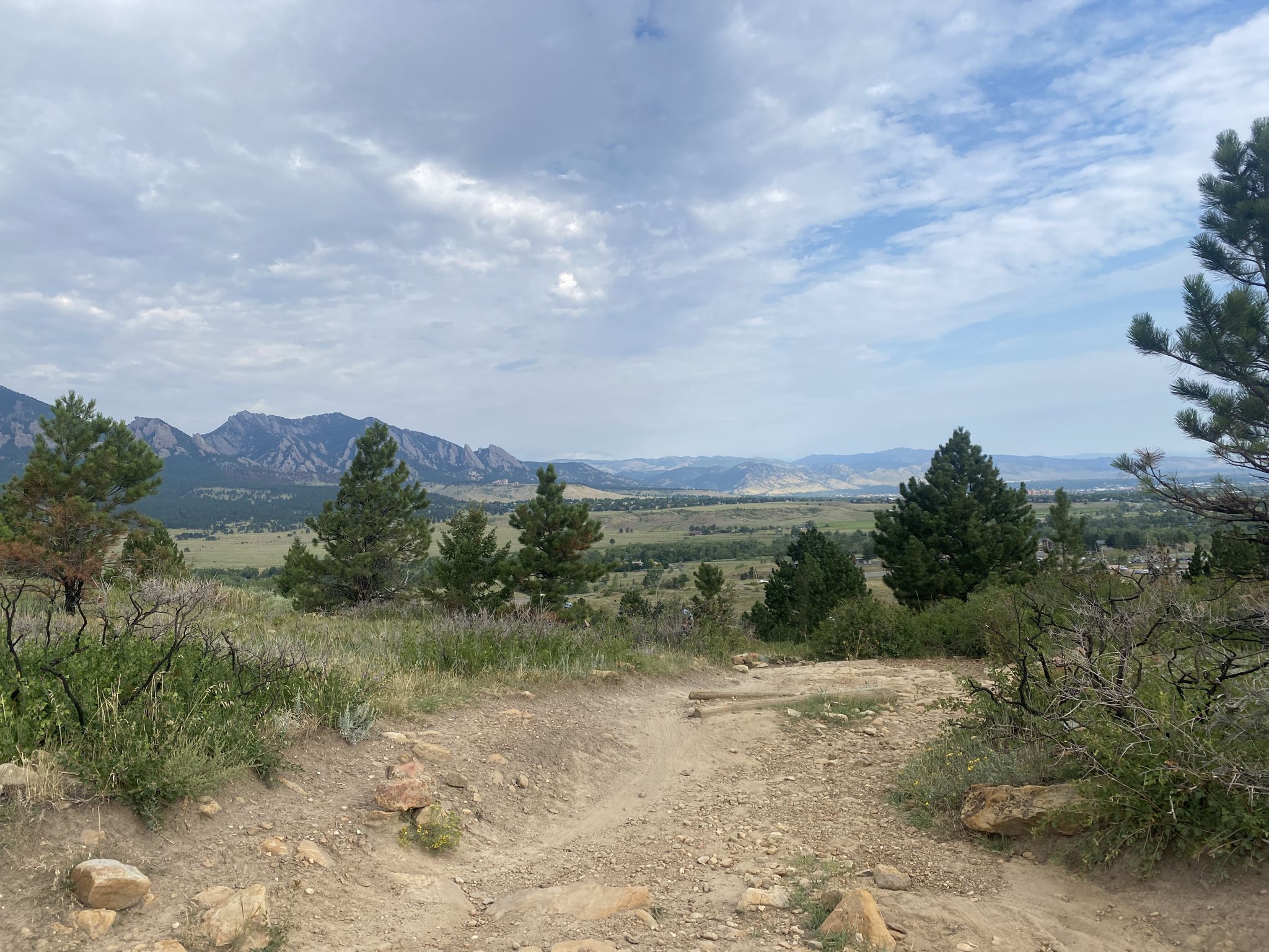 Dirt path overlooking a valley with distant mountains under cloudy sky. - Greenbelt Plateau, Community Ditch and Flatirons Vista Loop