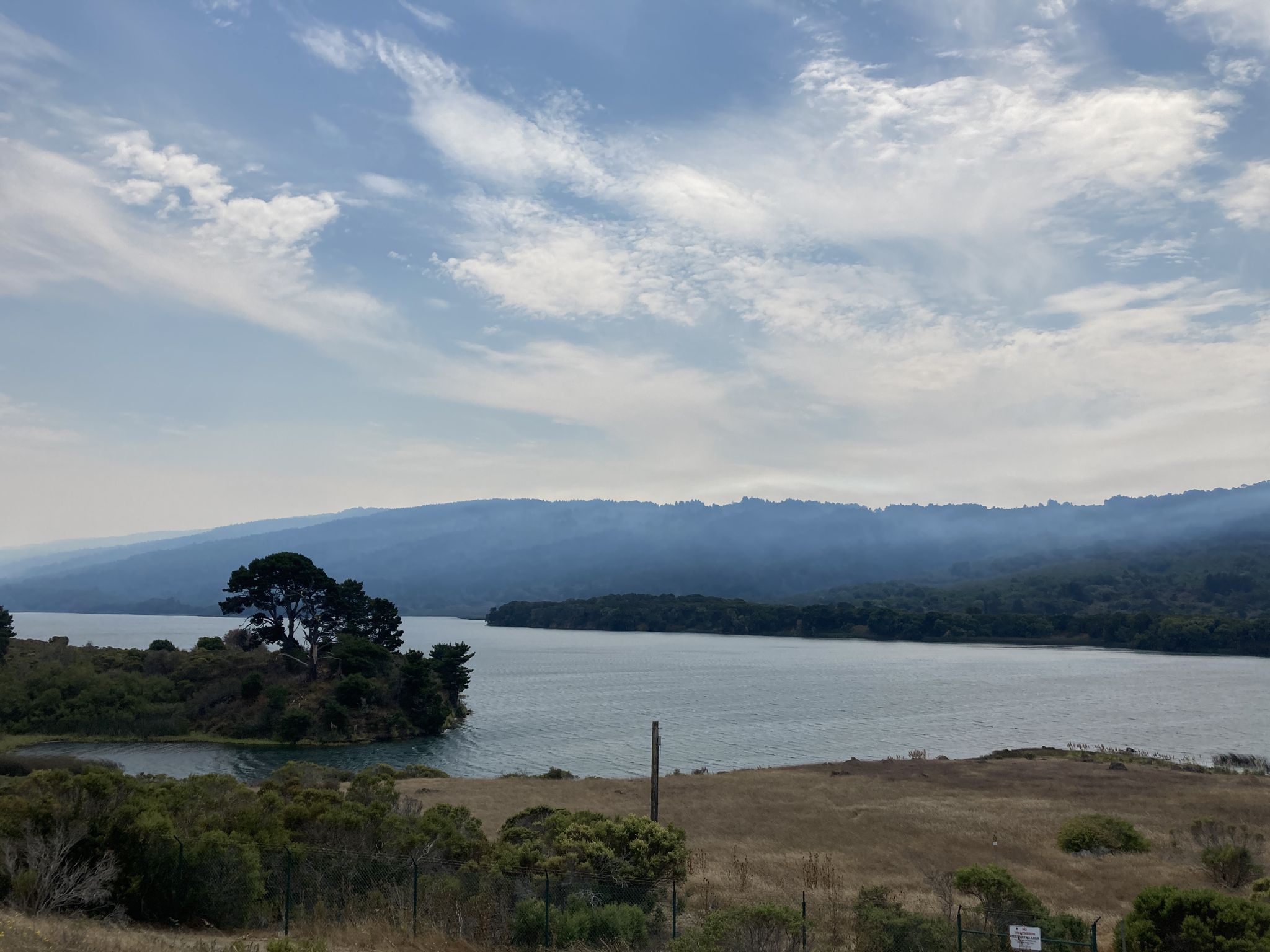 Wide view of a lake with distant hills under a cloudy sky. - Half Moon Bay loop from Redwood City via Purisima Creek Road