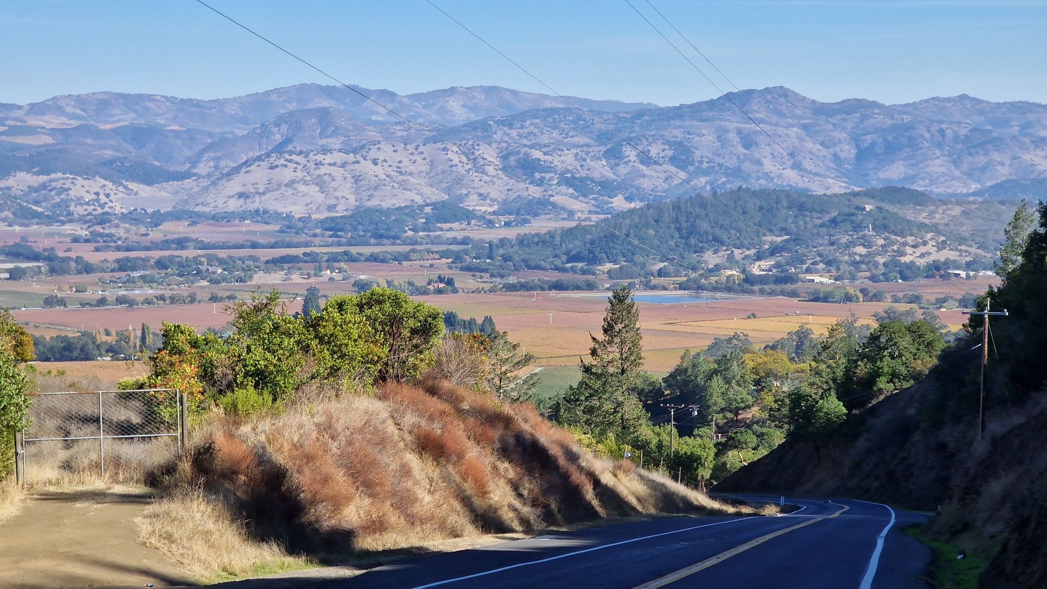 A scenic overlook of a vast valley with vineyards and distant mountains. - Napa Valley Vine Trail – The French Laundry loop from Yountville