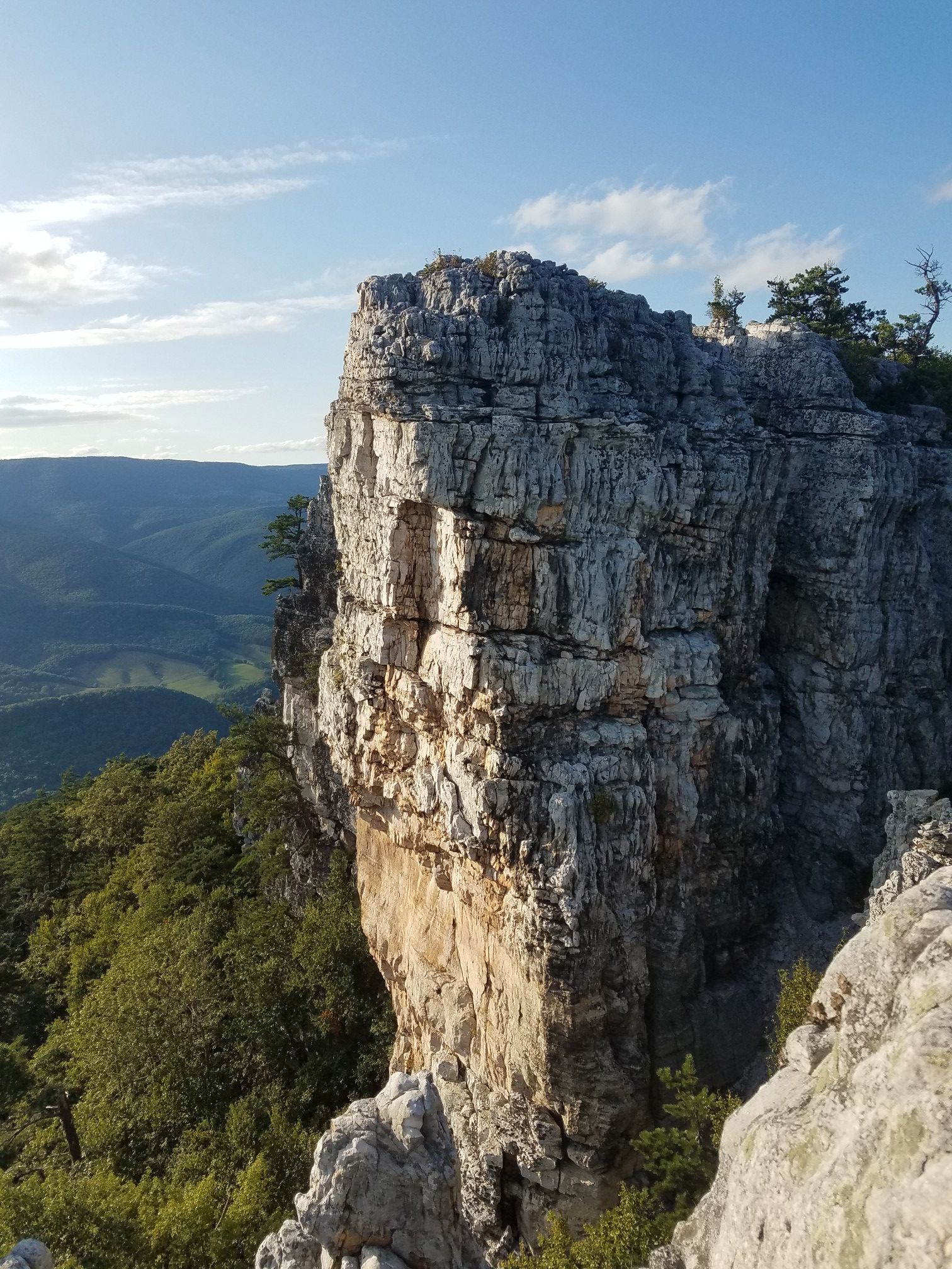 A towering, rugged rock formation overlooking distant mountains in golden light. - North Fork Mountain Trail to Chimney Top