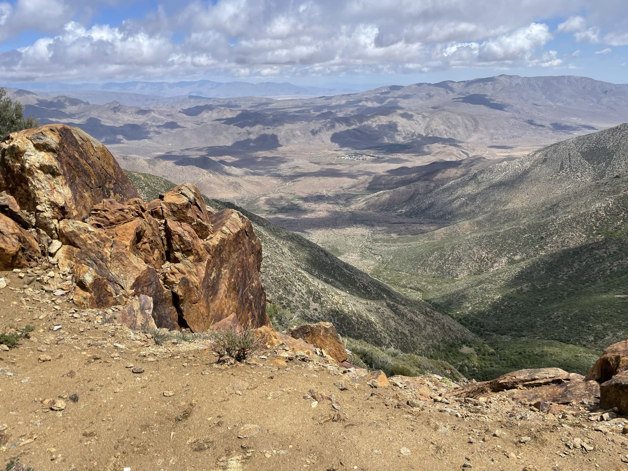 Rocky outcrop overlooking a wide, arid mountain valley under a cloudy sky. - Kwaaymii Point via Pacific Crest Trail