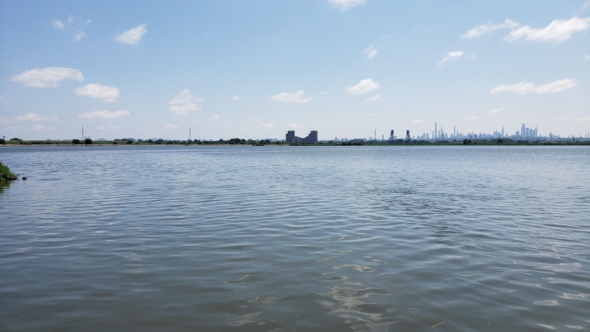Wide shot of calm water under a blue sky, distant industrial skyline. - Transco and Saw Mill Creek Trail Loop