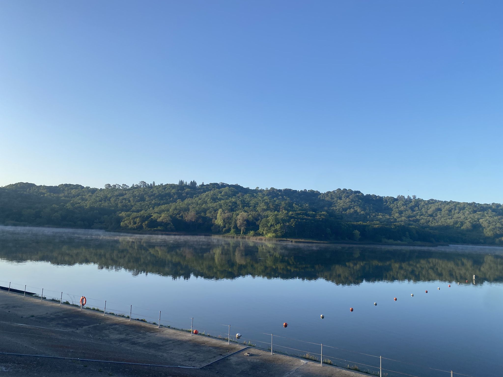 Calm lake reflecting lush green hills under a clear blue sky. - Rim Trail to Lafayette Viewpoint