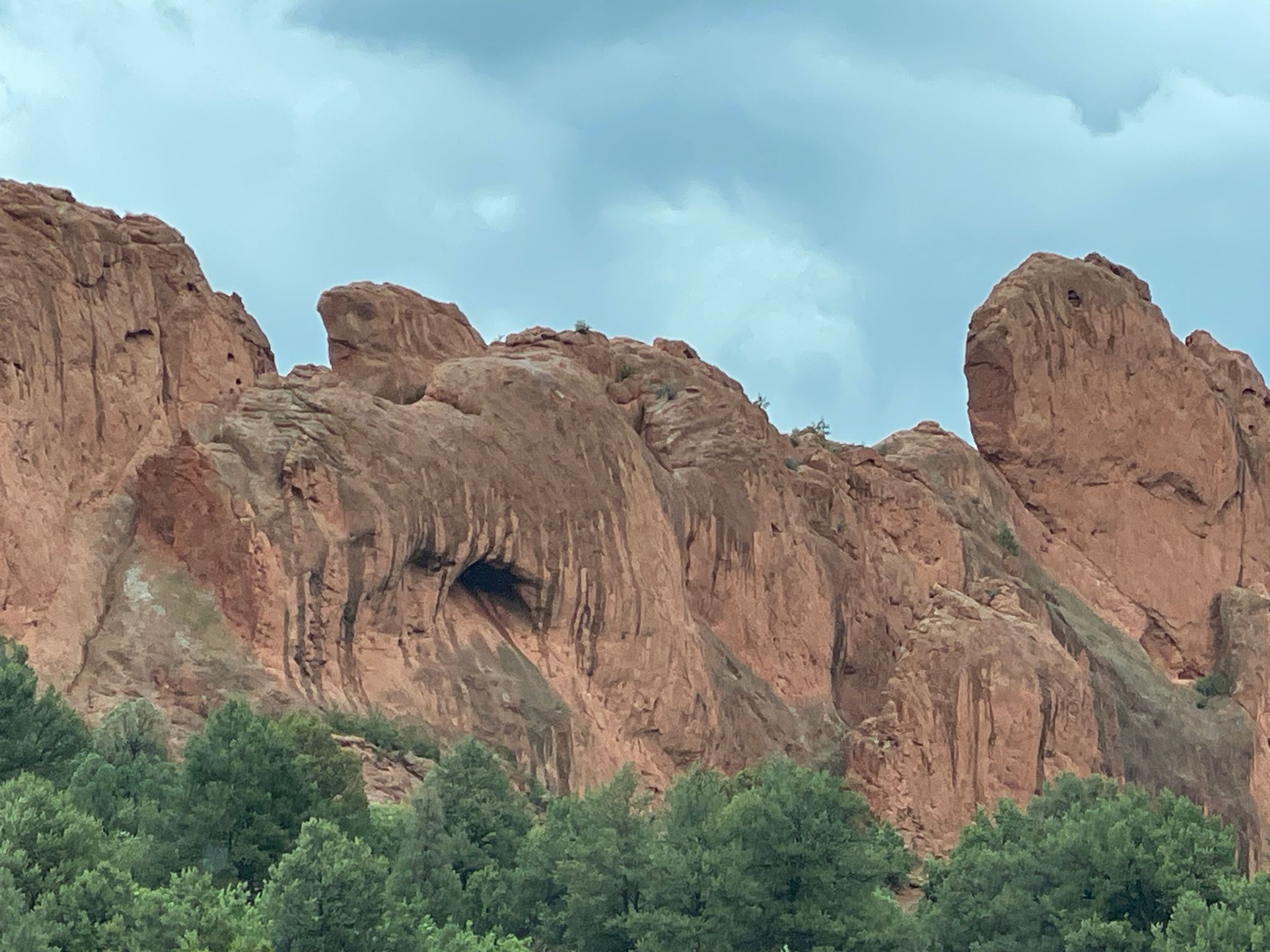 Detailed view of a rugged red rock cliff with a dark cave opening. - Steamboat Rock – Garden of the Gods loop from Manitou Depot