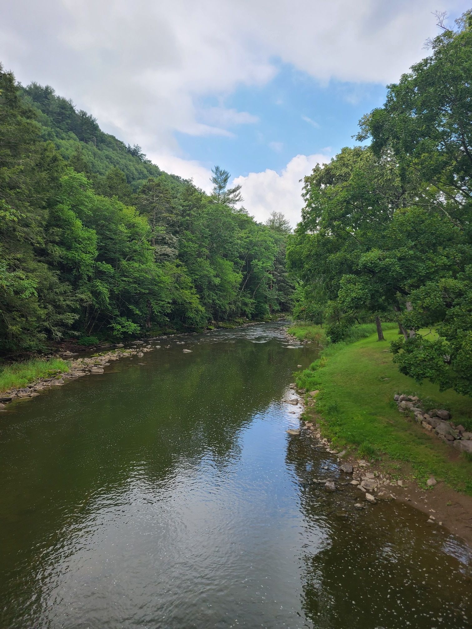 Green river winding through a lush, forested valley under a partly cloudy sky. - Poe Valley State Park loop via Penns Path